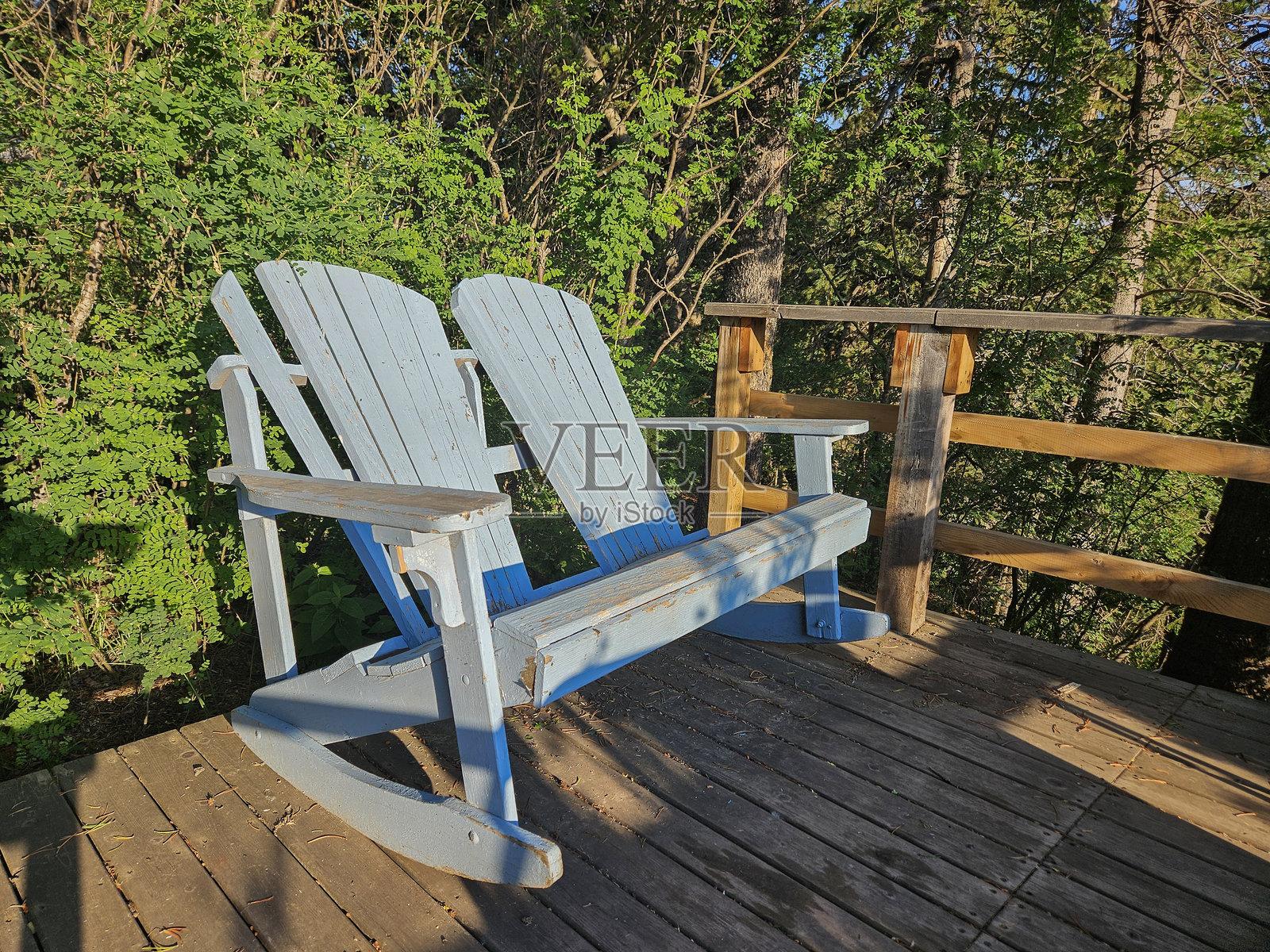 两把蓝色的木制阿迪朗达克露台椅并排放置在木质户外露台上。照片摄影图片