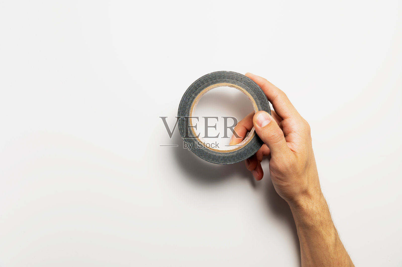 男人手持绿色胶带,背景为白色,特写。可留空白以便添加文字。照片摄影图片