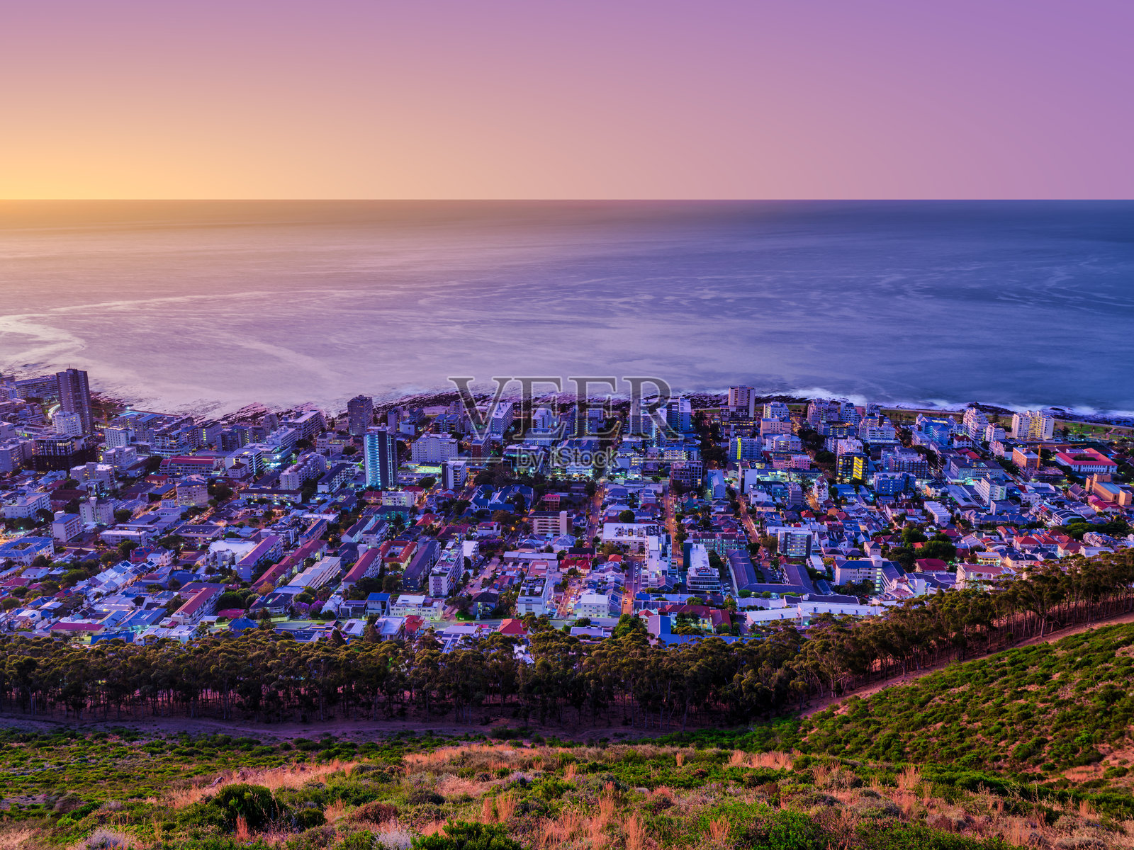 开普敦,南非,日落后灯光璀璨的海角建筑和街道,前景是信号山的山坡。照片摄影图片