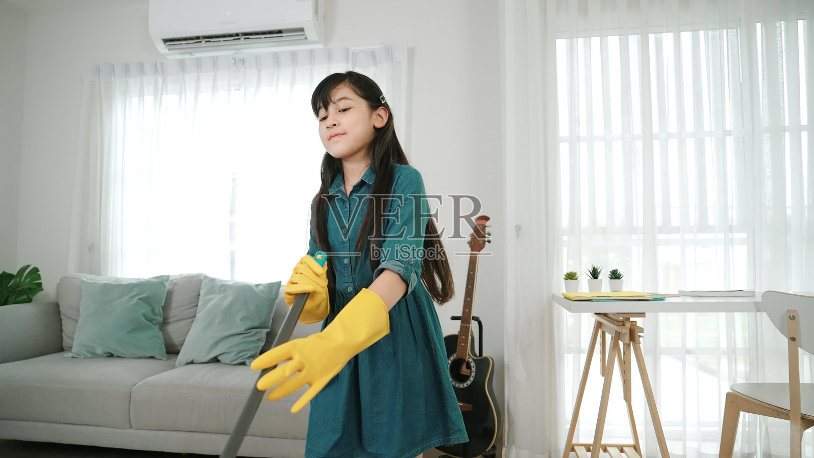 快乐的女儿在客厅里一边听音乐一边拖地。教育学。照片摄影图片