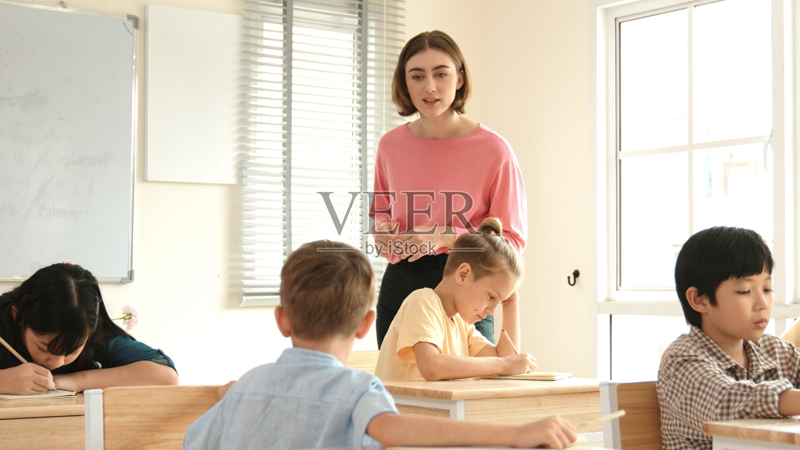 专业教师在课堂上向白人男孩讲解课堂作业。教育学。照片摄影图片