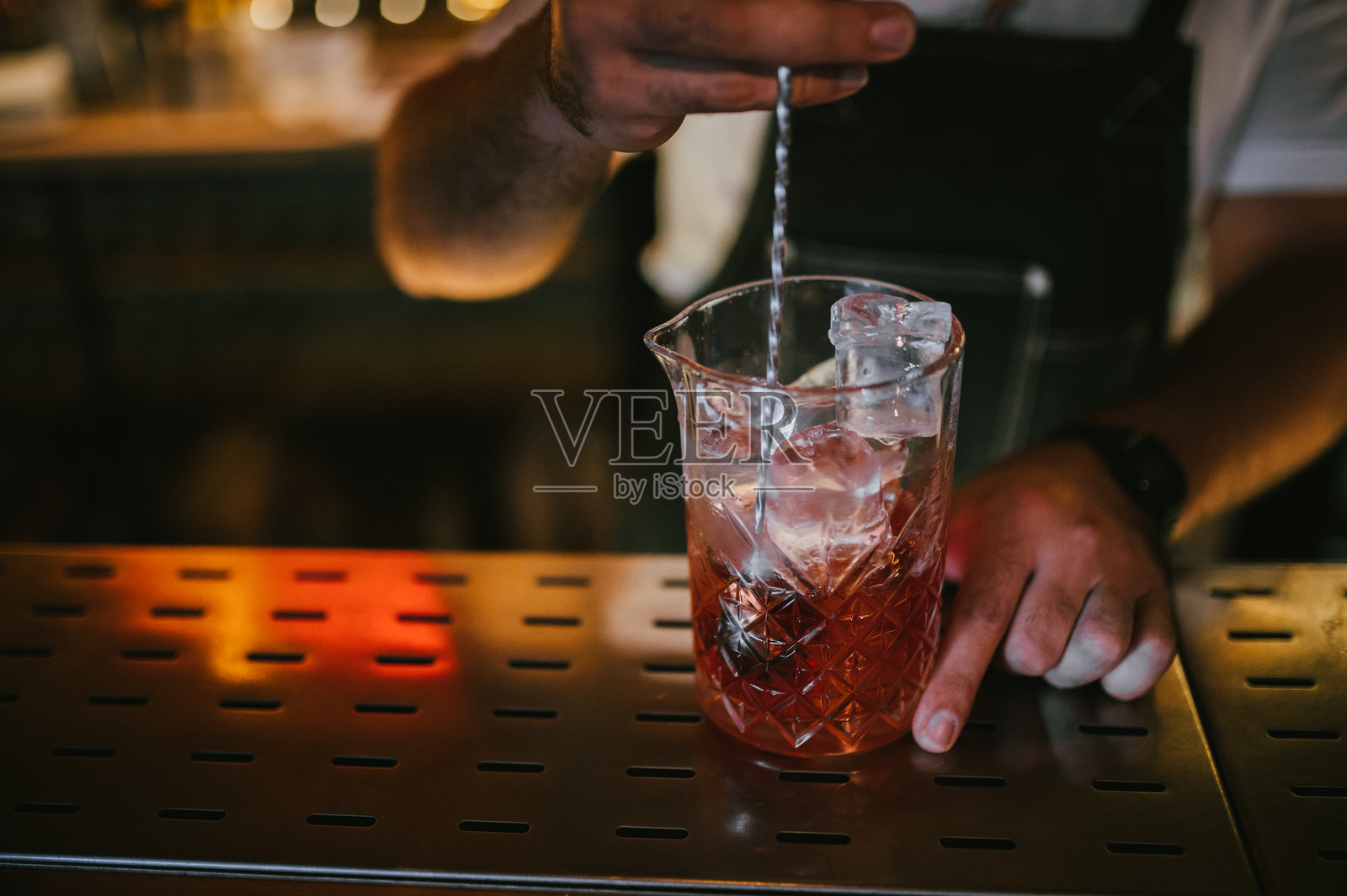 男性调酒师正在准备橙皮尼格罗尼鸡尾酒。照片摄影图片