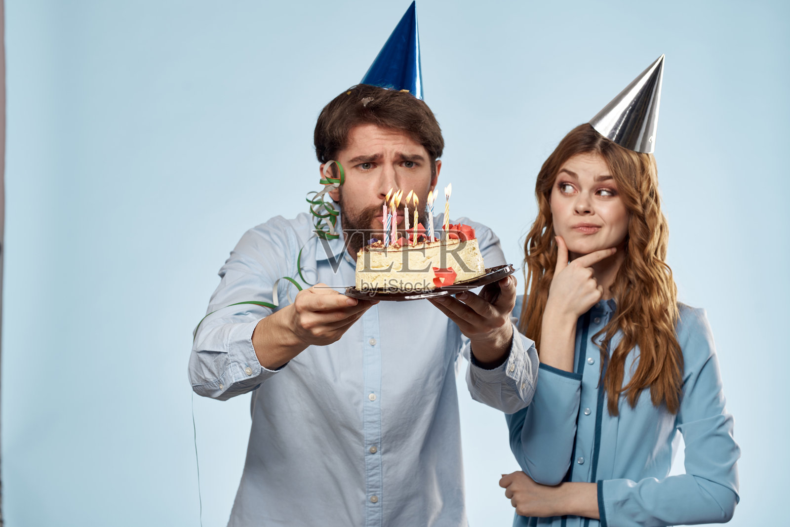 情感丰富的男人与蛋糕和美丽的女人在蓝色背景的派对迪斯科中照片摄影图片