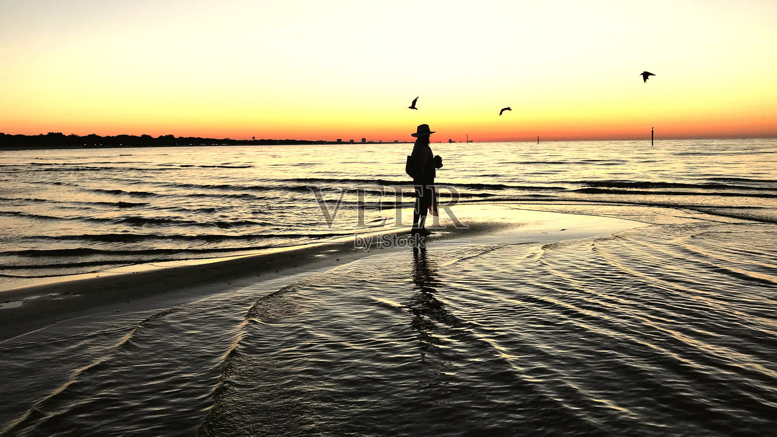 海滩上站着的女人剪影,背景是晴朗的天空照片摄影图片