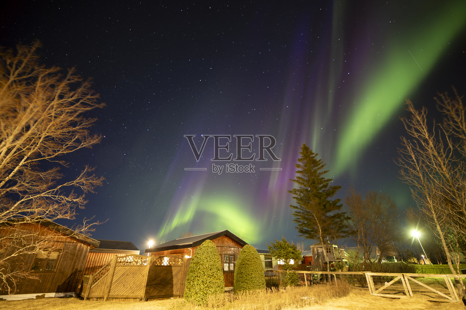 2024年4月16日,冰岛赫拉市。北极光在河边的城市上空闪耀。照片摄影图片