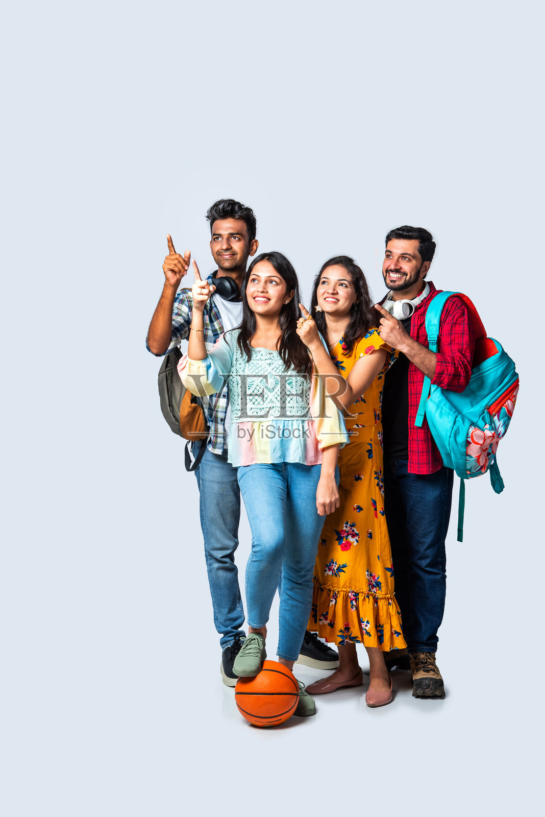 四个年轻的印度亚裔大学朋友带着背包,书,笔记本电脑,站在孤立的白色,在图书馆学习照片摄影图片