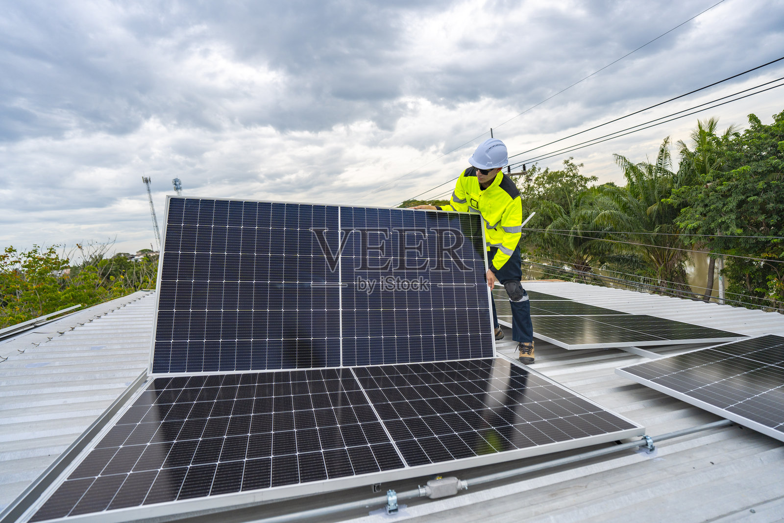 一名熟练的技术人员在屋顶上调整太阳能电池板,强调向可持续能源的转型。穿戴安全装备的工人在可再生能源安装中展现出精确的技术。照片摄影图片