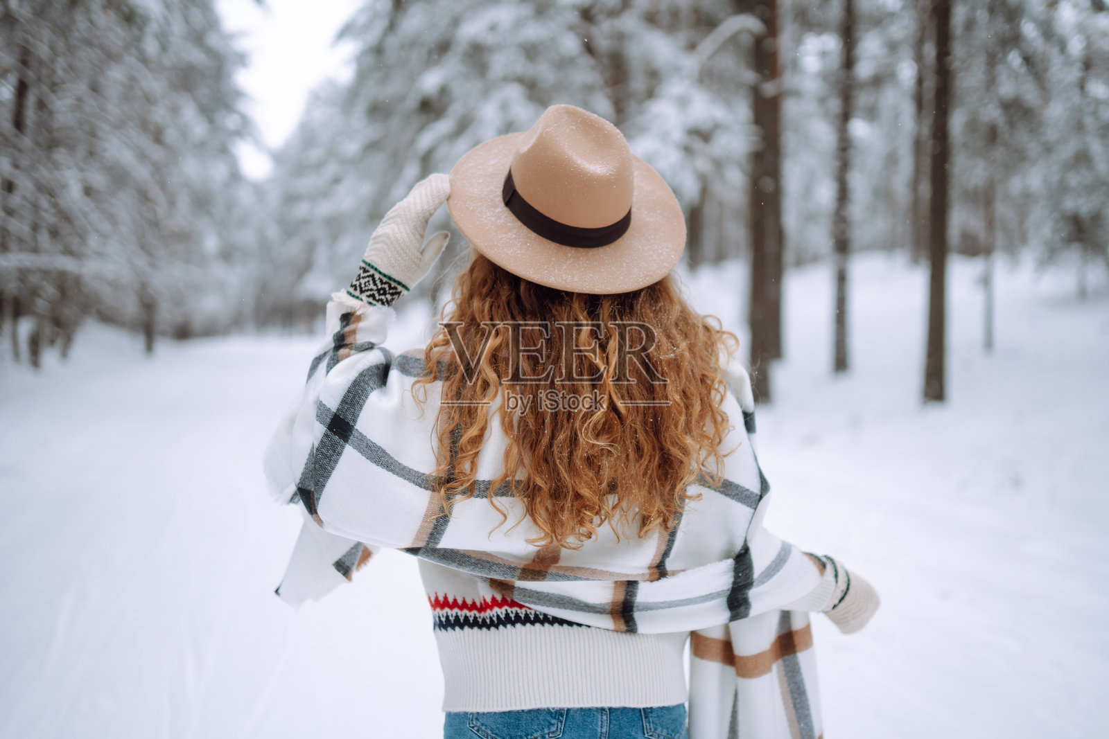 女人背对着雪-covered树木站立。照片摄影图片