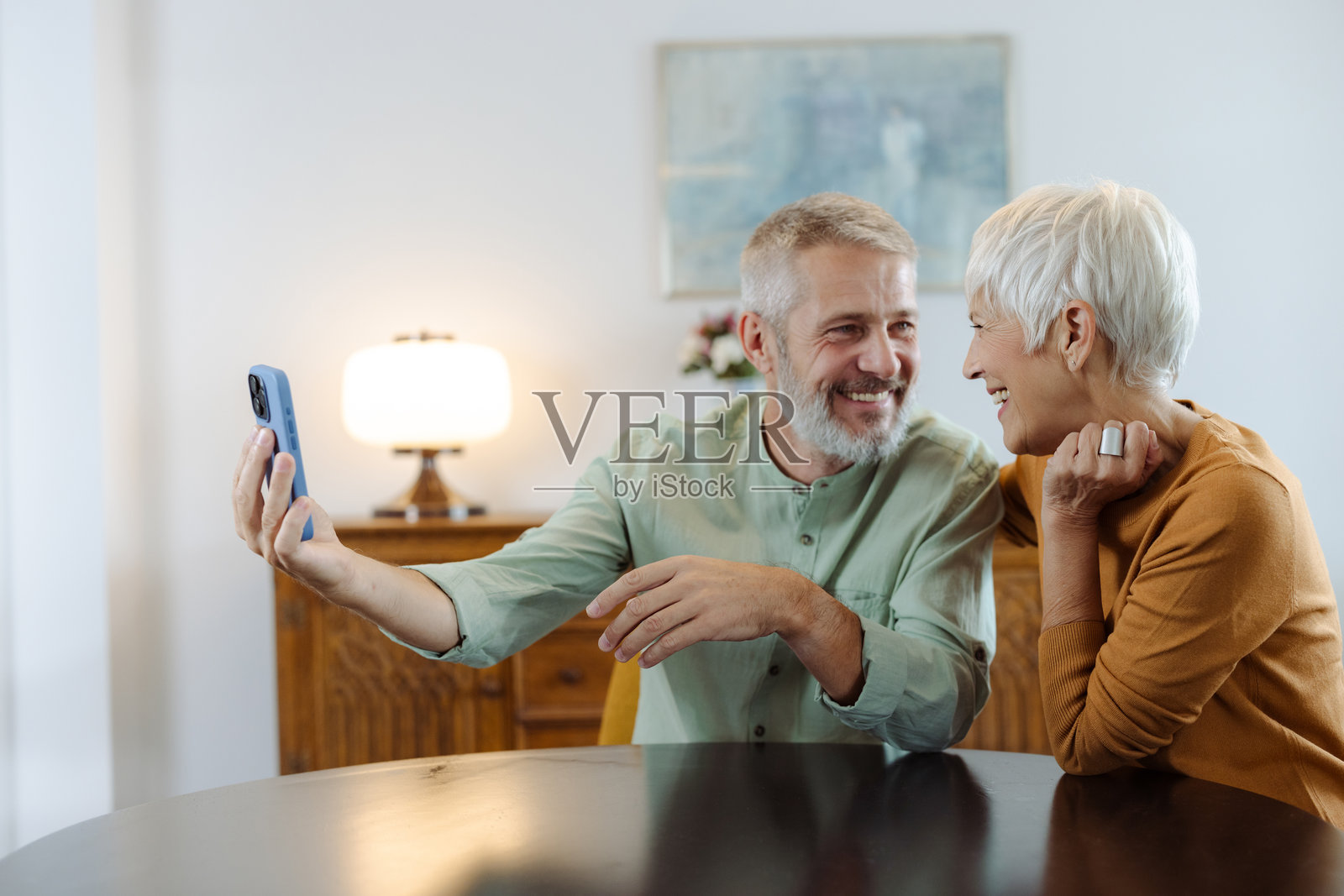 老年夫妇在客厅的桌子旁坐着,用手机自拍照片摄影图片