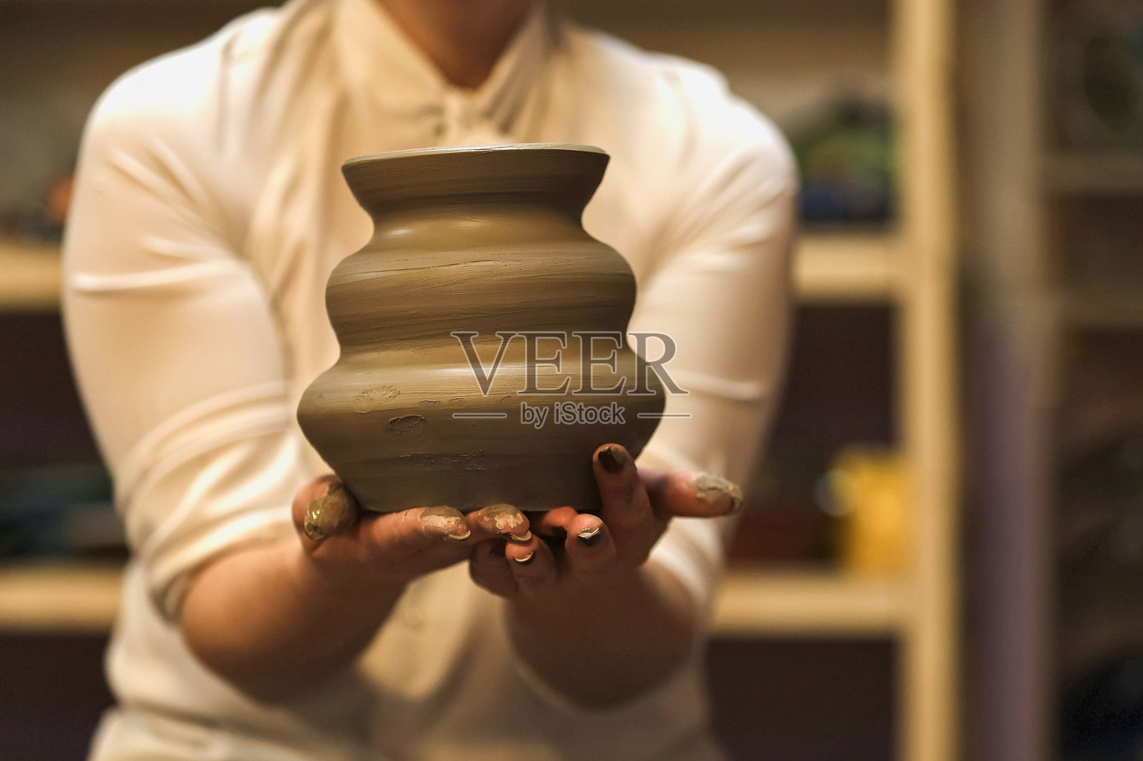 手握绿色陶瓷壶的特写。照片摄影图片