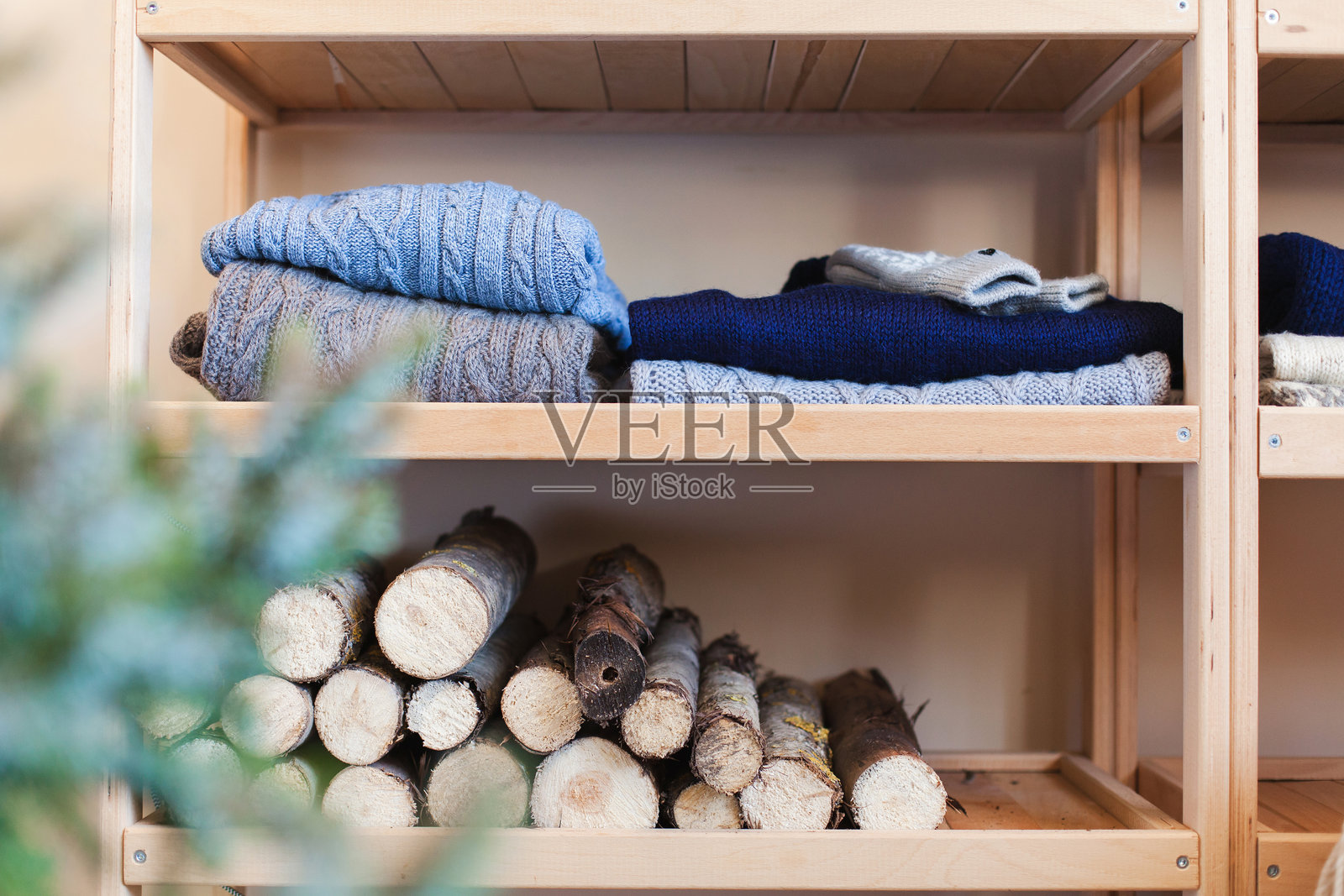 乡村风格的圣诞室内装饰。架子上摆放着蓝色、灰色的针织毛衣和木柴。装饰精美的房间。照片摄影图片