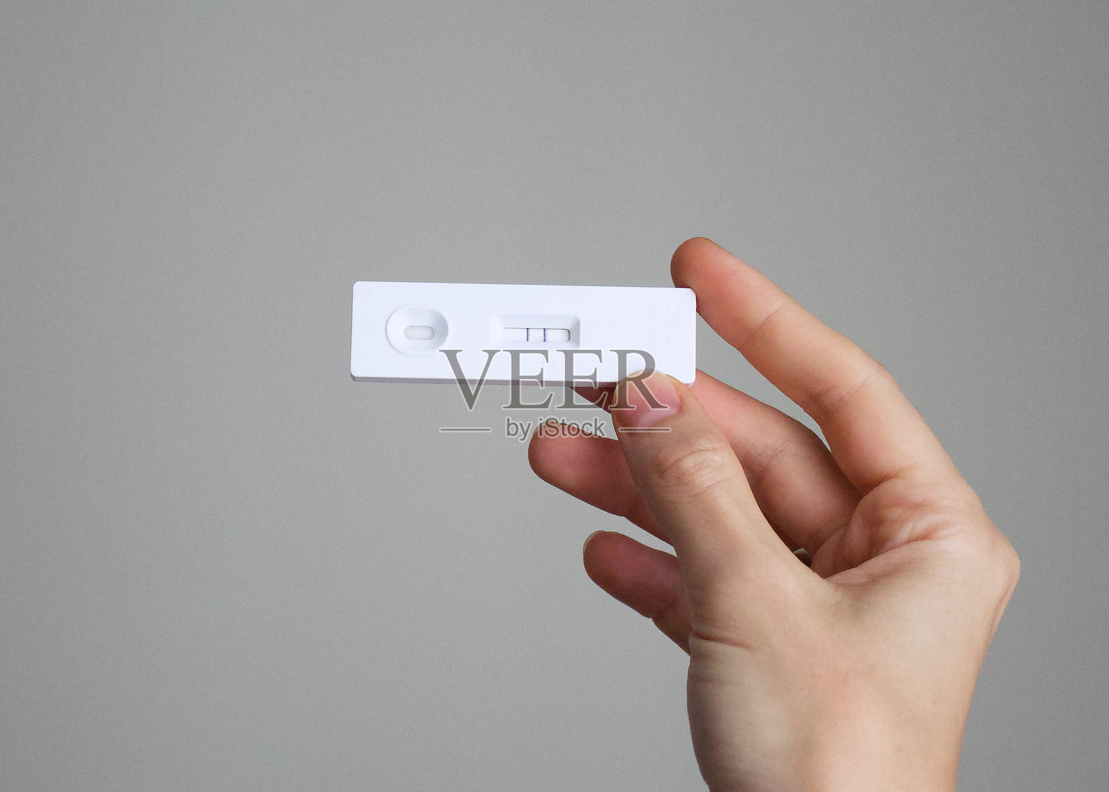 手中显示阳性结果的抗原新冠病毒检测,意味着该人感染了病毒,需要治疗。照片摄影图片