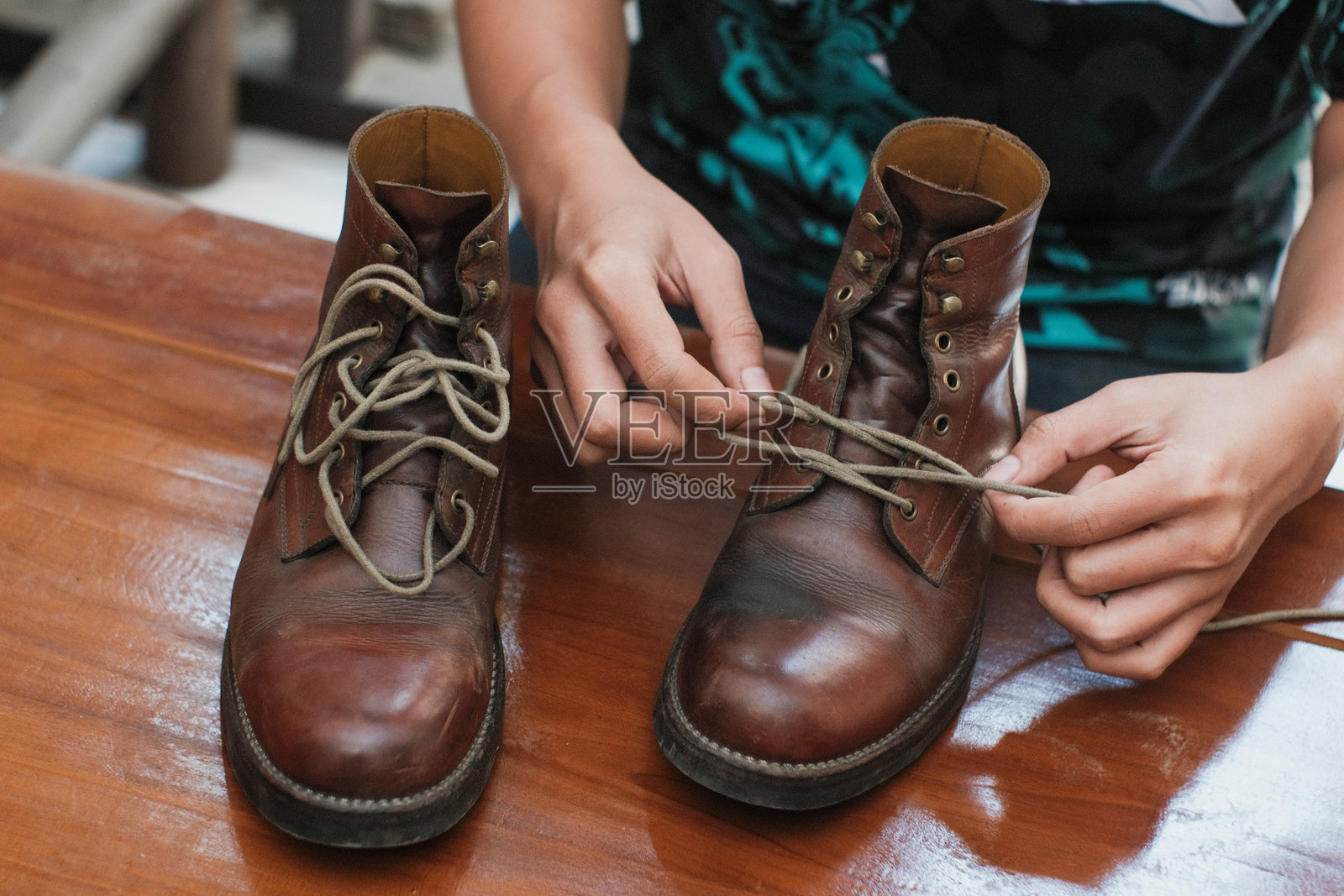 男人在木桌上解开靴子鞋带的特写手部。照片摄影图片