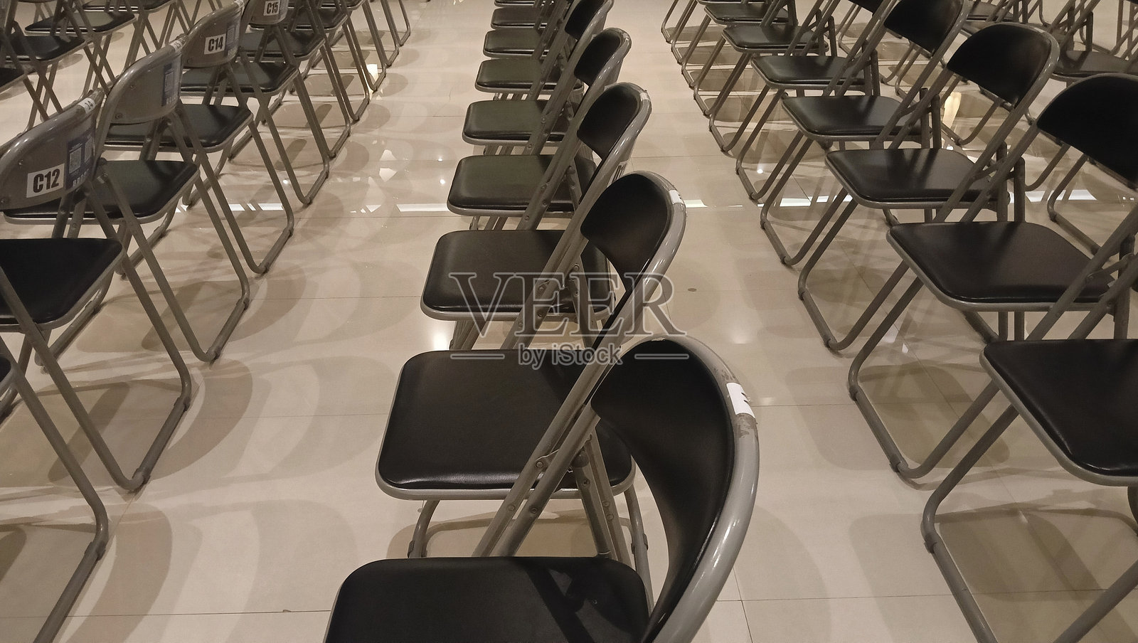 许多黑色椅子在一个大房间里排成一排。空椅子 – 椅子排。照片摄影图片
