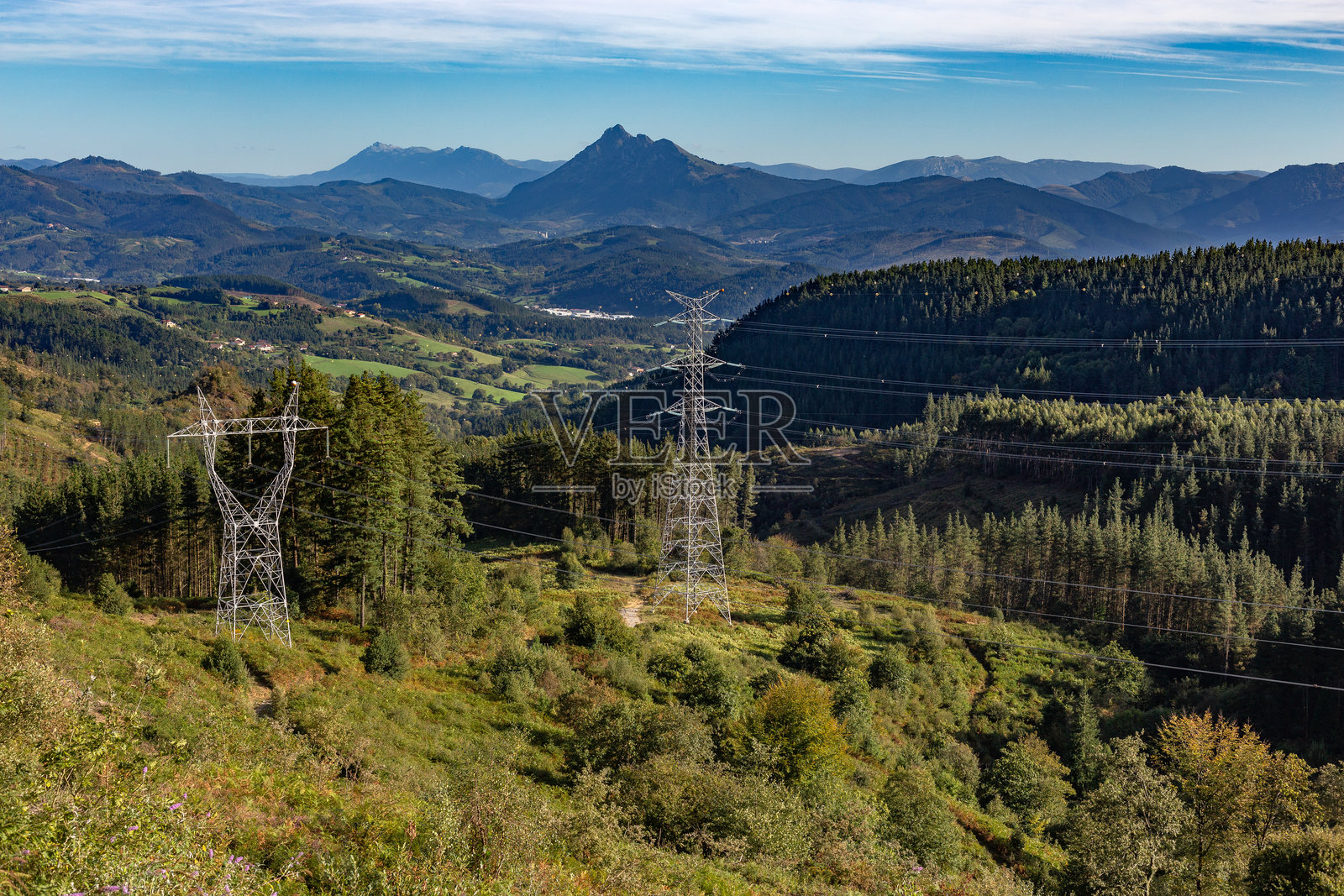 位于自然环境中的森林山脉中的电力塔。照片摄影图片