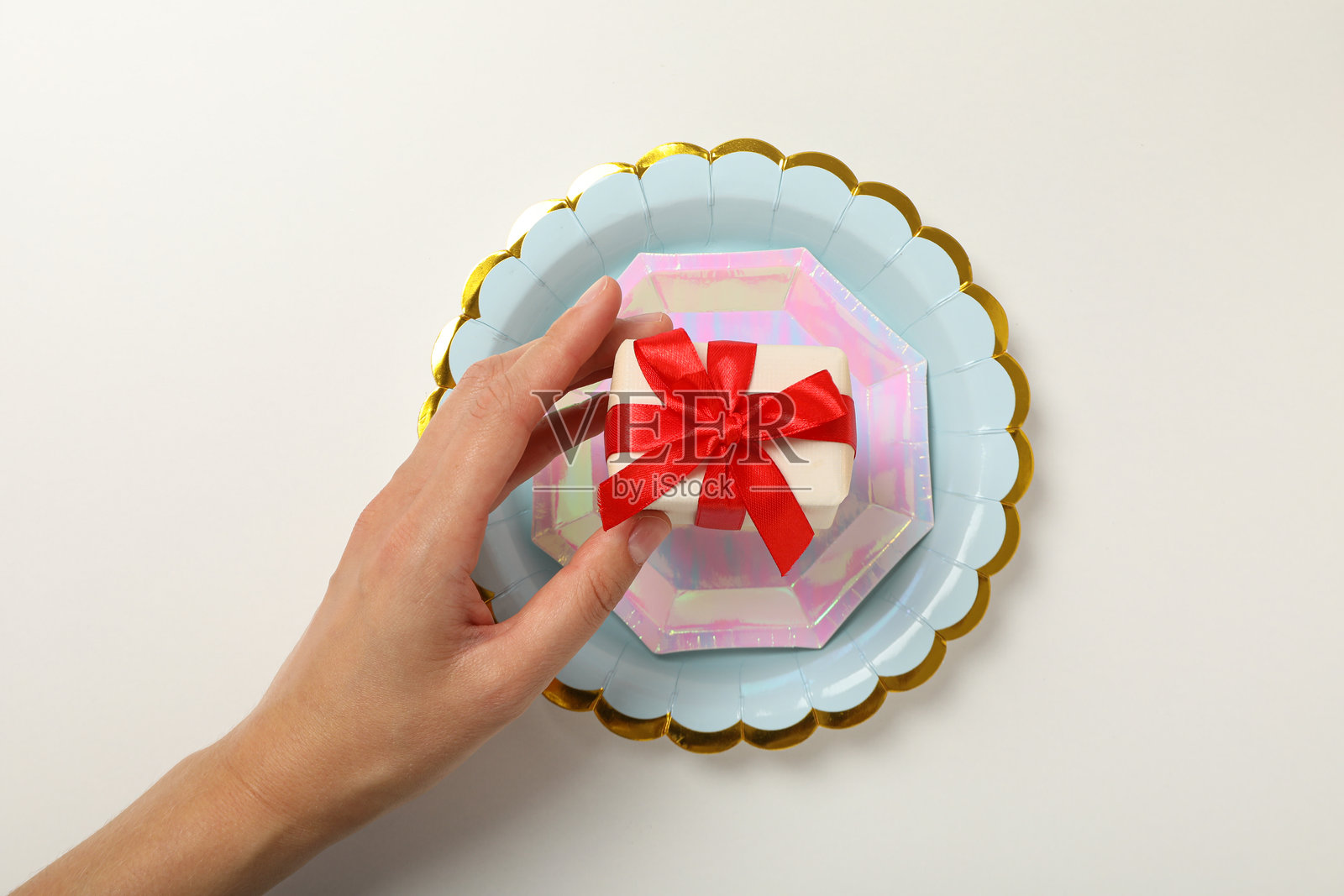 手中拿着礼品盒,白色背景上的盘子,俯视图照片摄影图片