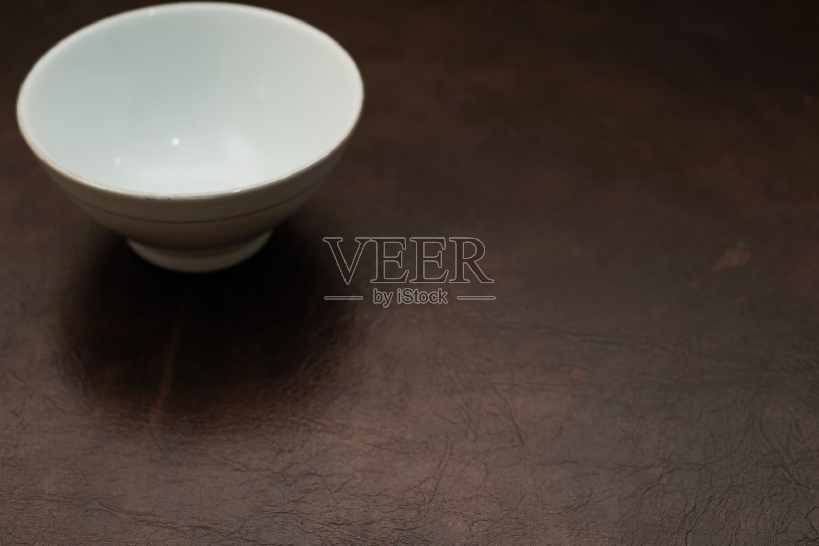 白色迷你陶瓷碗的俯视图,背景为棕色照片摄影图片