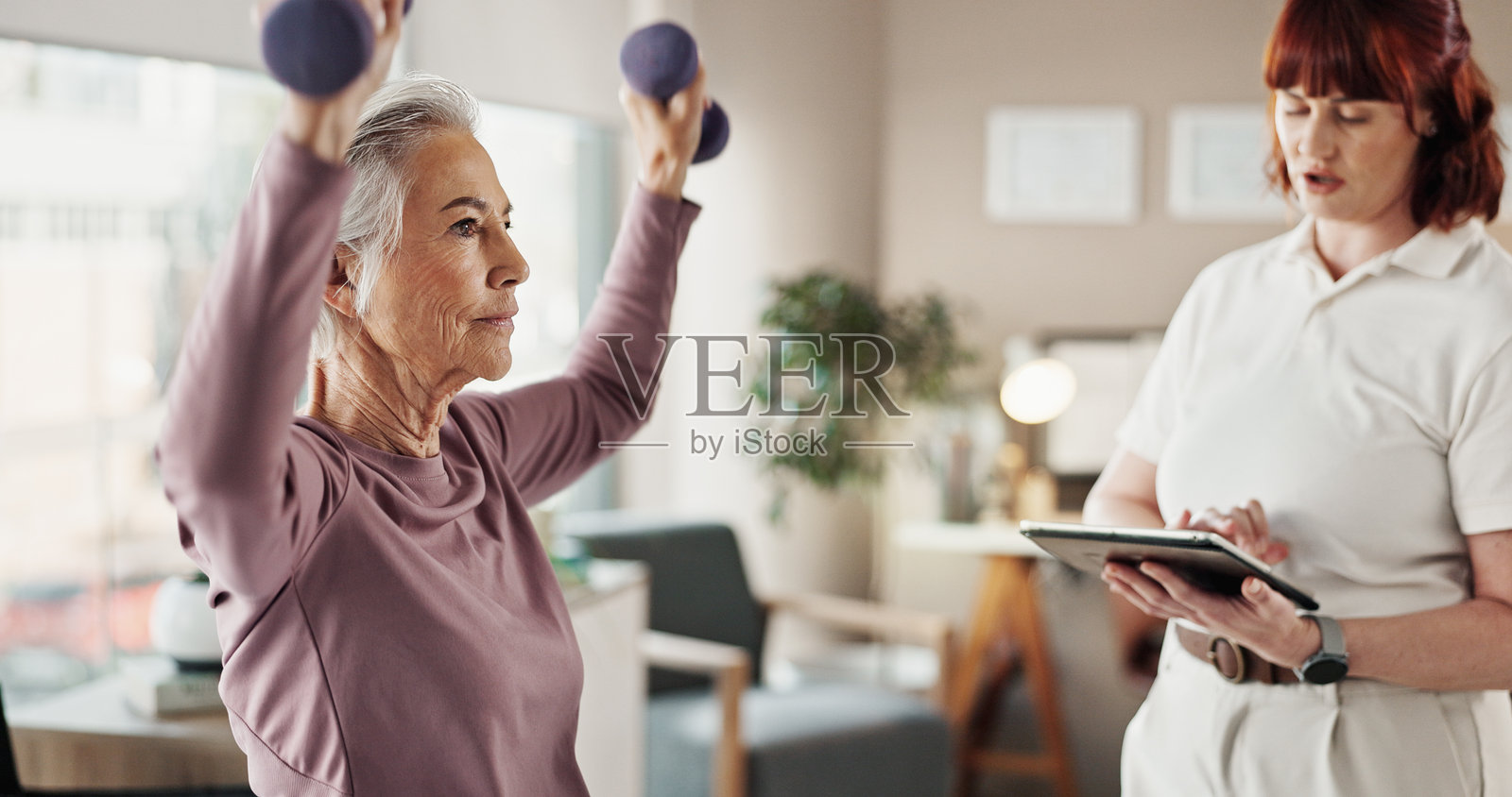 平板电脑、物理治疗师和使用哑铃的老年女性,关注健康、移动性和物理治疗。医疗保健、医疗咨询以及与成熟患者一起进行力量训练、康复或帮助。照片摄影图片