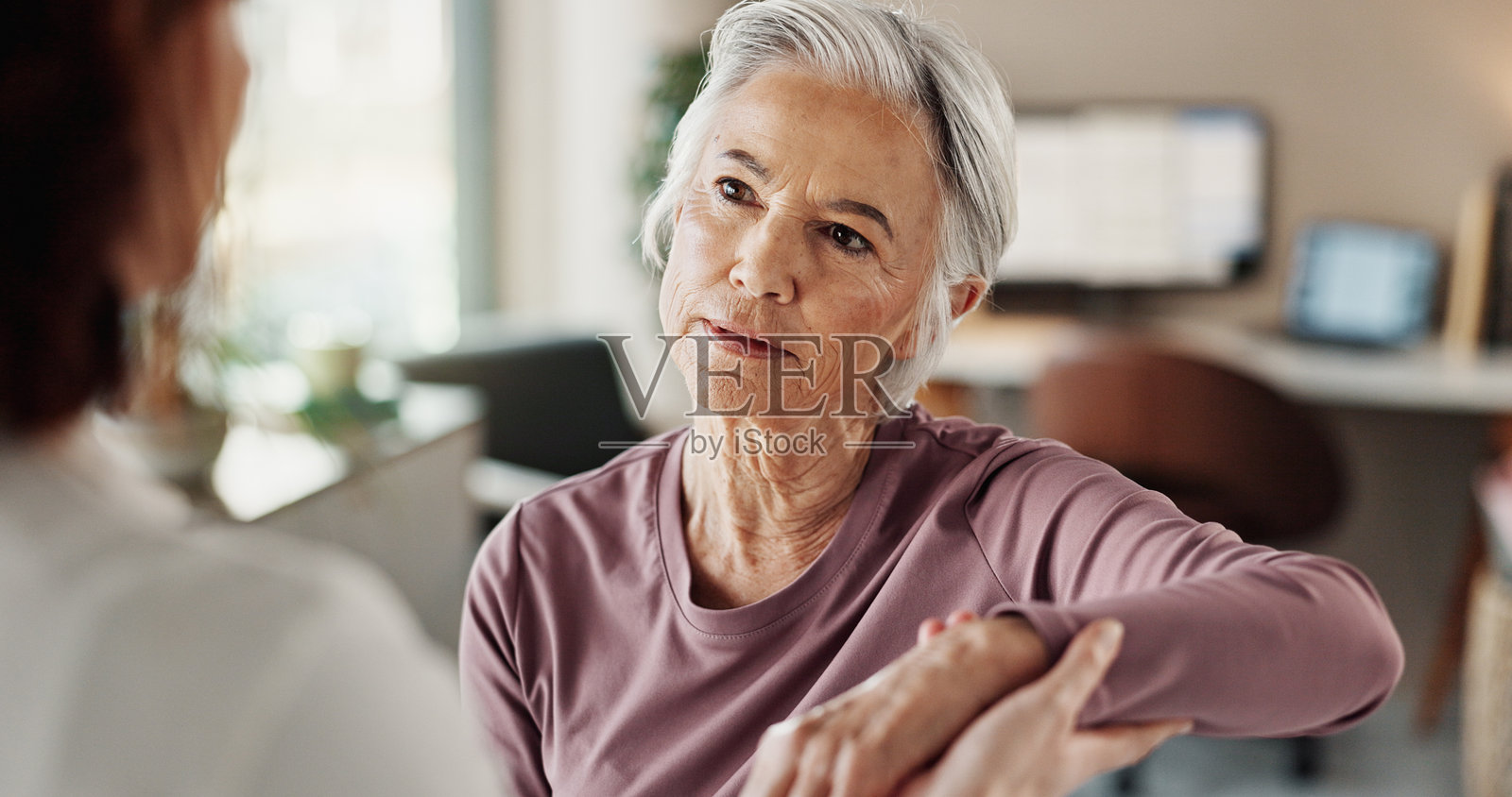 老年女性因手臂疼痛接受物理治疗、咨询和医疗帮助,涉及医学和关节炎。老年患者与医生进行物理治疗、医疗和康复,以获得支持。照片摄影图片