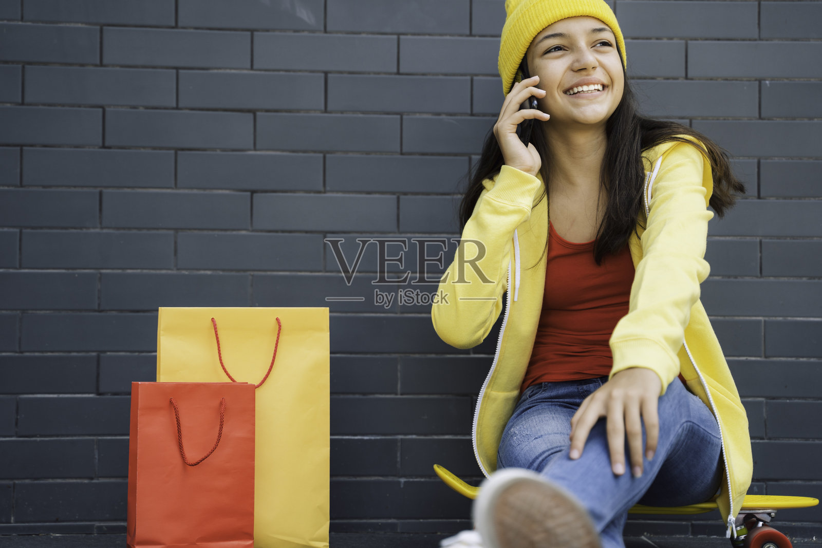 快乐的少女在打电话,旁边有购物袋照片摄影图片