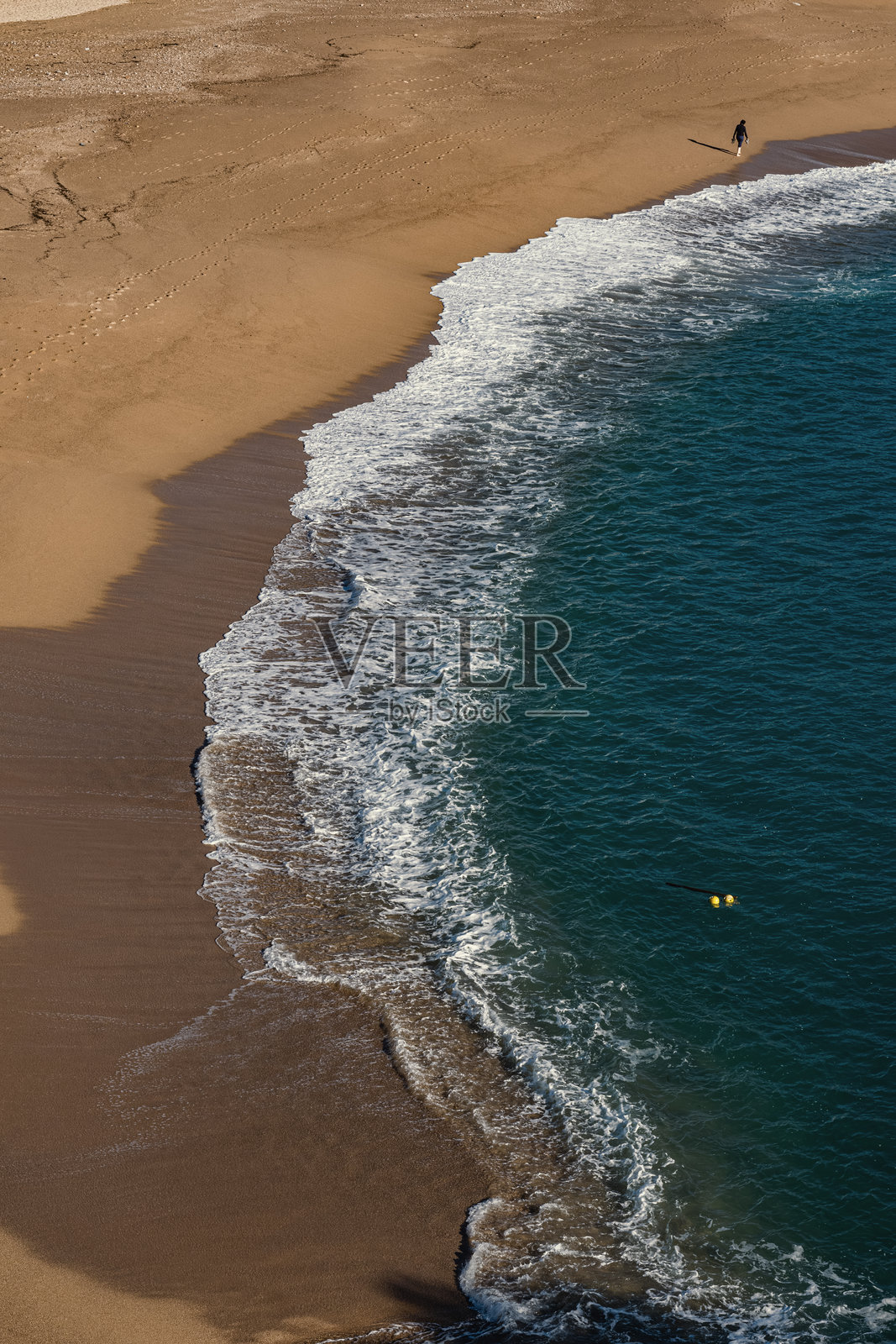 远处一个模糊的人在海滩上赤脚行走。照片摄影图片