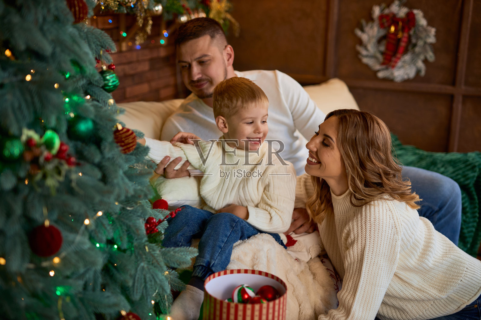 温暖地拥抱在圣诞树旁的幸福家庭照片摄影图片