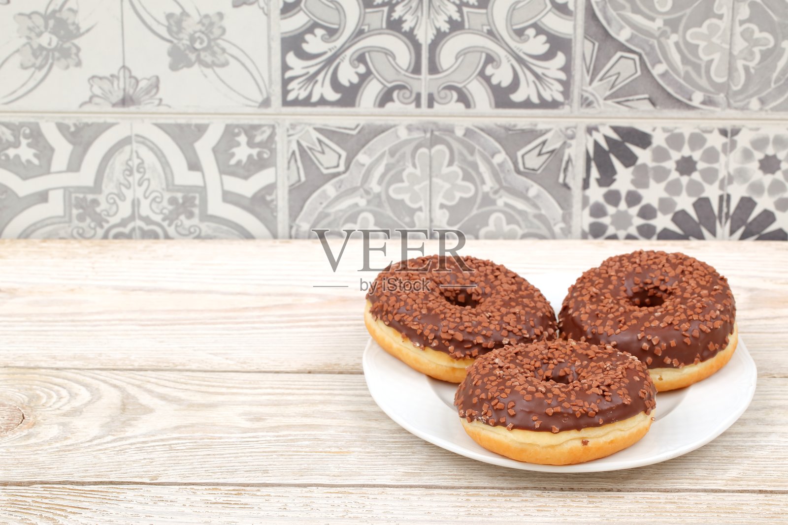 一盘装满美味巧克力甜甜圈,上面慷慨地撒满了五彩缤纷的糖屑照片摄影图片