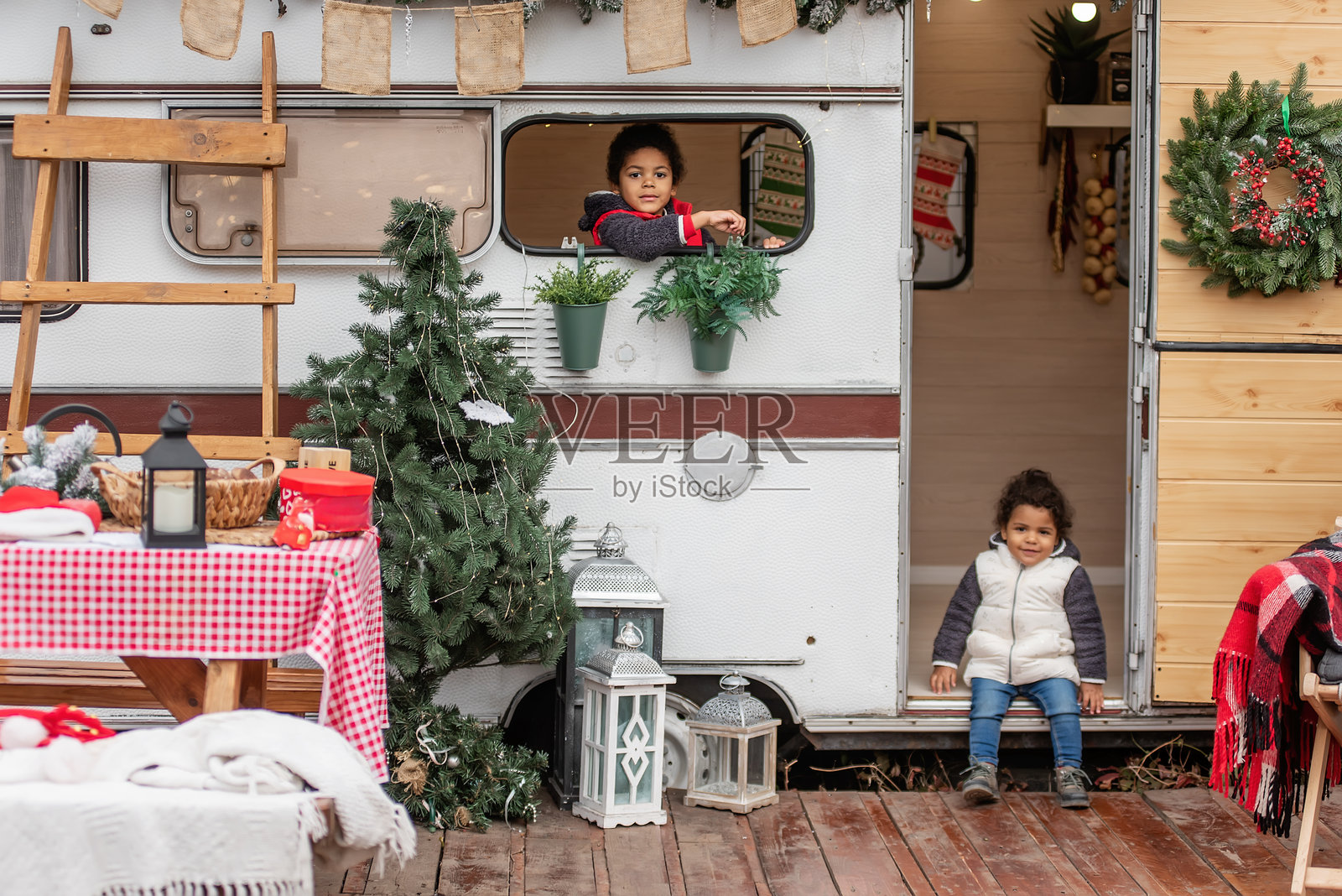 兴奋的孩子们在节日露营车旁庆祝圣诞节照片摄影图片
