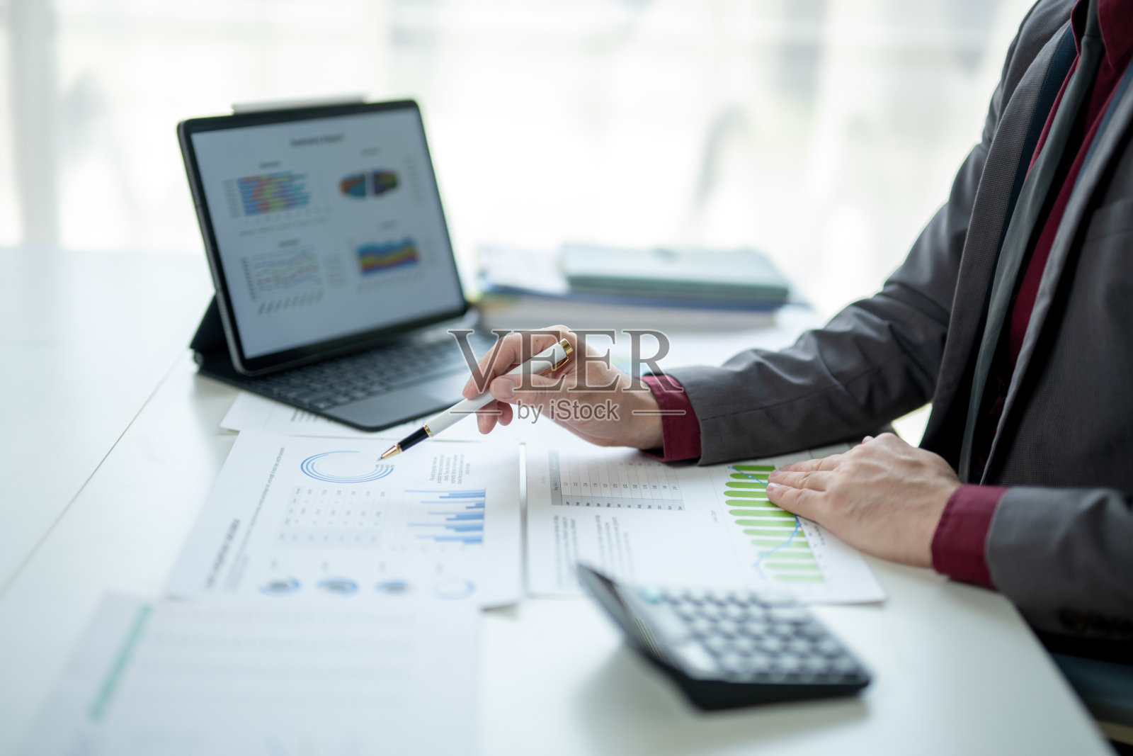 一名男子坐在桌子前,面前有一台笔记本电脑和一台计算器。照片摄影图片