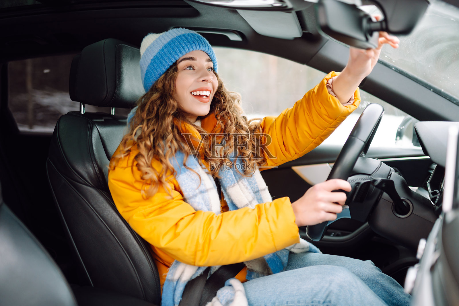 年轻女性在冬季高速公路上白天驾驶汽车。照片摄影图片