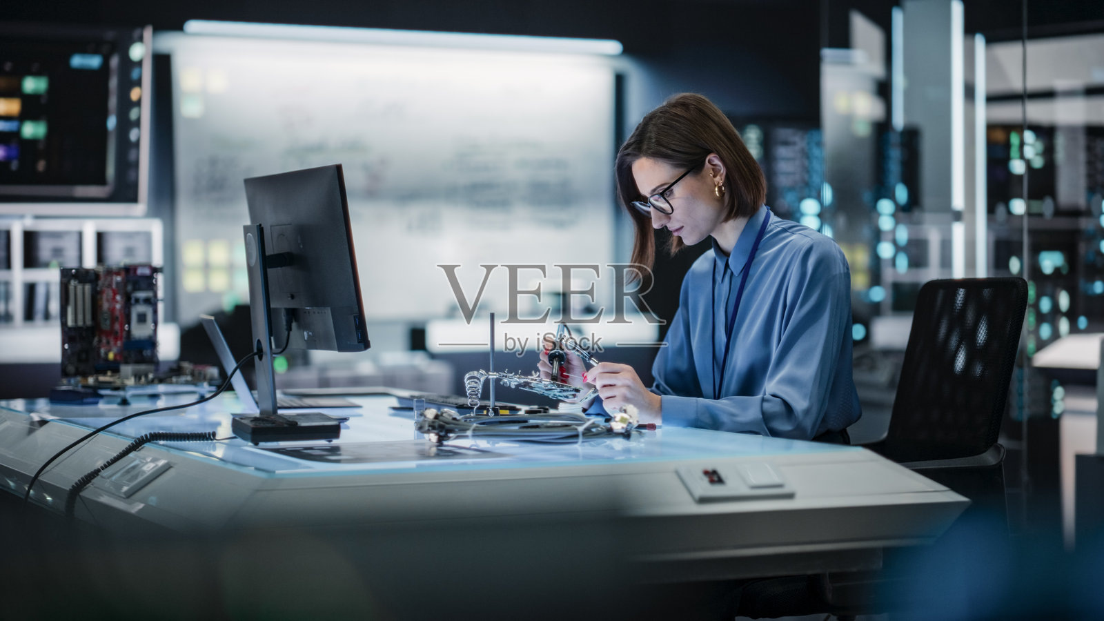 女性专家在一家技术先进的公司焊接电路板的肖像。专注的女性工程师在制造研究设施中进行项目工作,测试理论。照片摄影图片