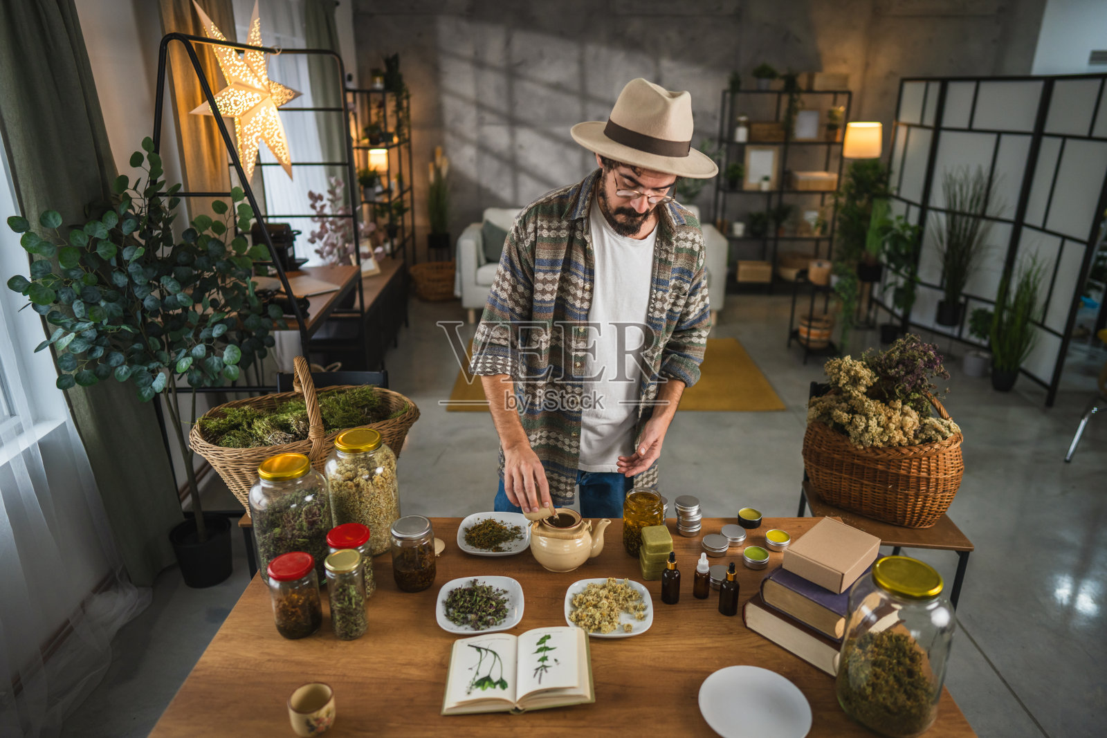 草药师在乡村工作室里将茶从茶壶倒入杯中照片摄影图片