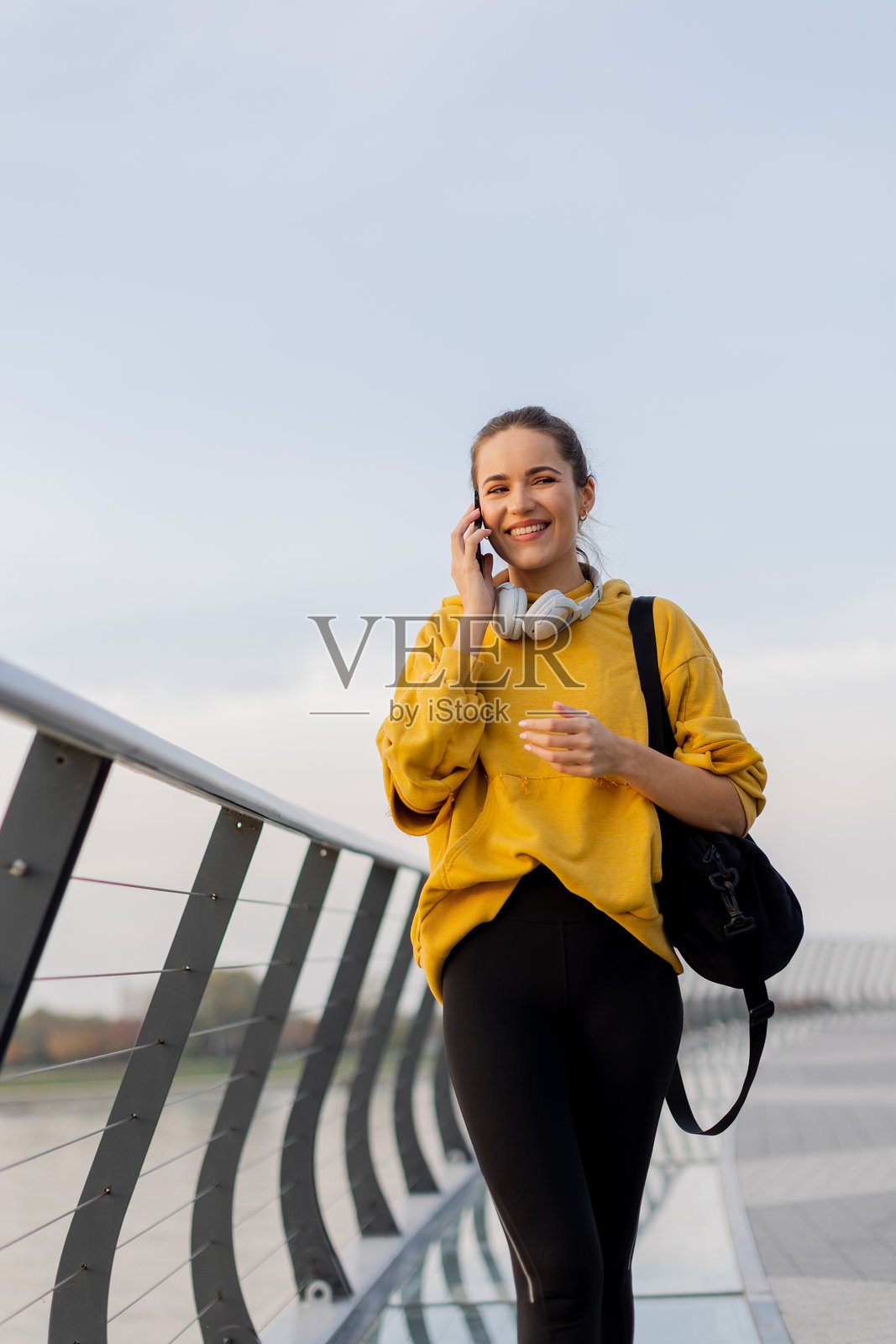 愉快的女性在现代桥上漫步,一边聊天一边享受黄昏时分水边宁静的城市风景。照片摄影图片