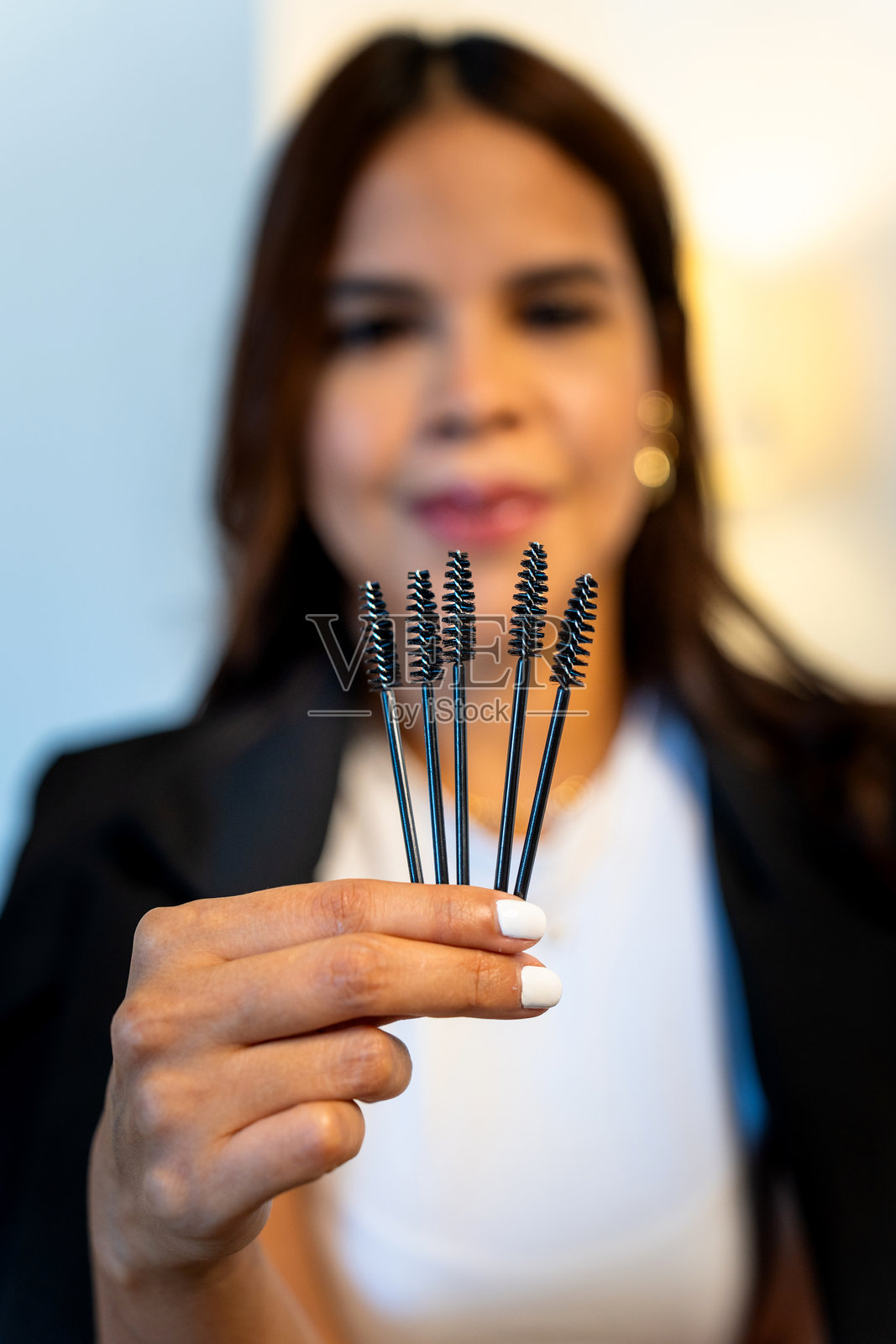 一位专业的拉丁女性在美容行业中手持眉刷的肖像。照片摄影图片