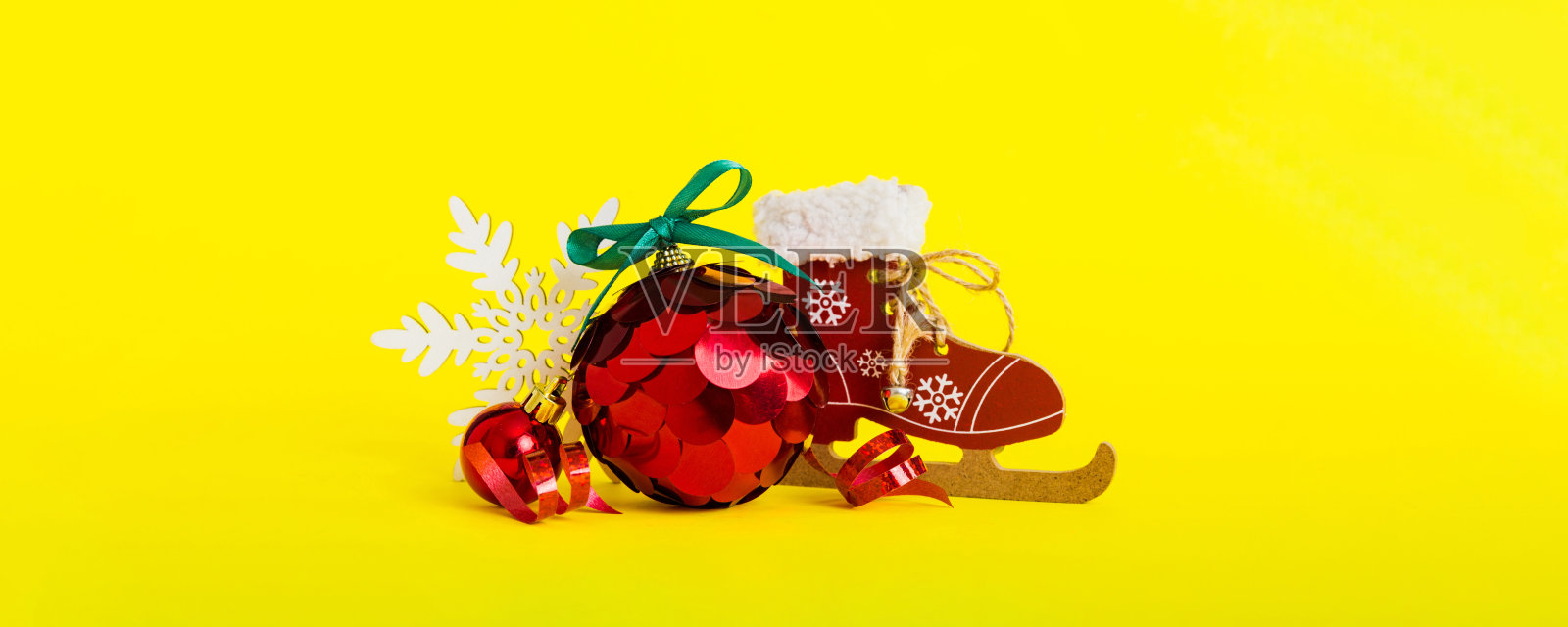 带有滑冰鞋的圣诞球,背景色彩丰富。装饰球与丝带蝴蝶结,留有空白空间。照片摄影图片