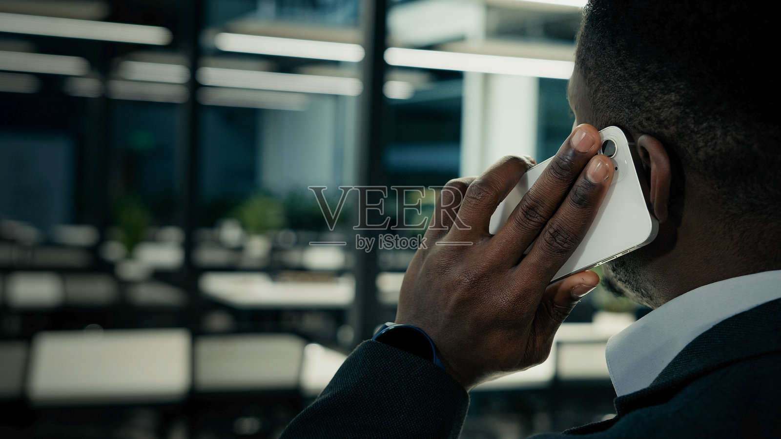 背影的非洲民族商人雇主首席执行官经理老板在室内办公室使用手机进行远程商务对话,利用现代科技进行电话沟通。照片摄影图片