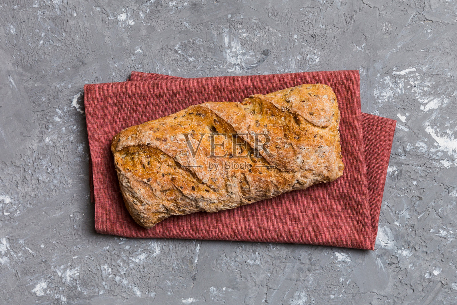 新鲜的面包在彩色桌子上,旁边有小麦和面筋。面包放在餐巾上,背景为乡村风格,俯视新鲜面包。照片摄影图片