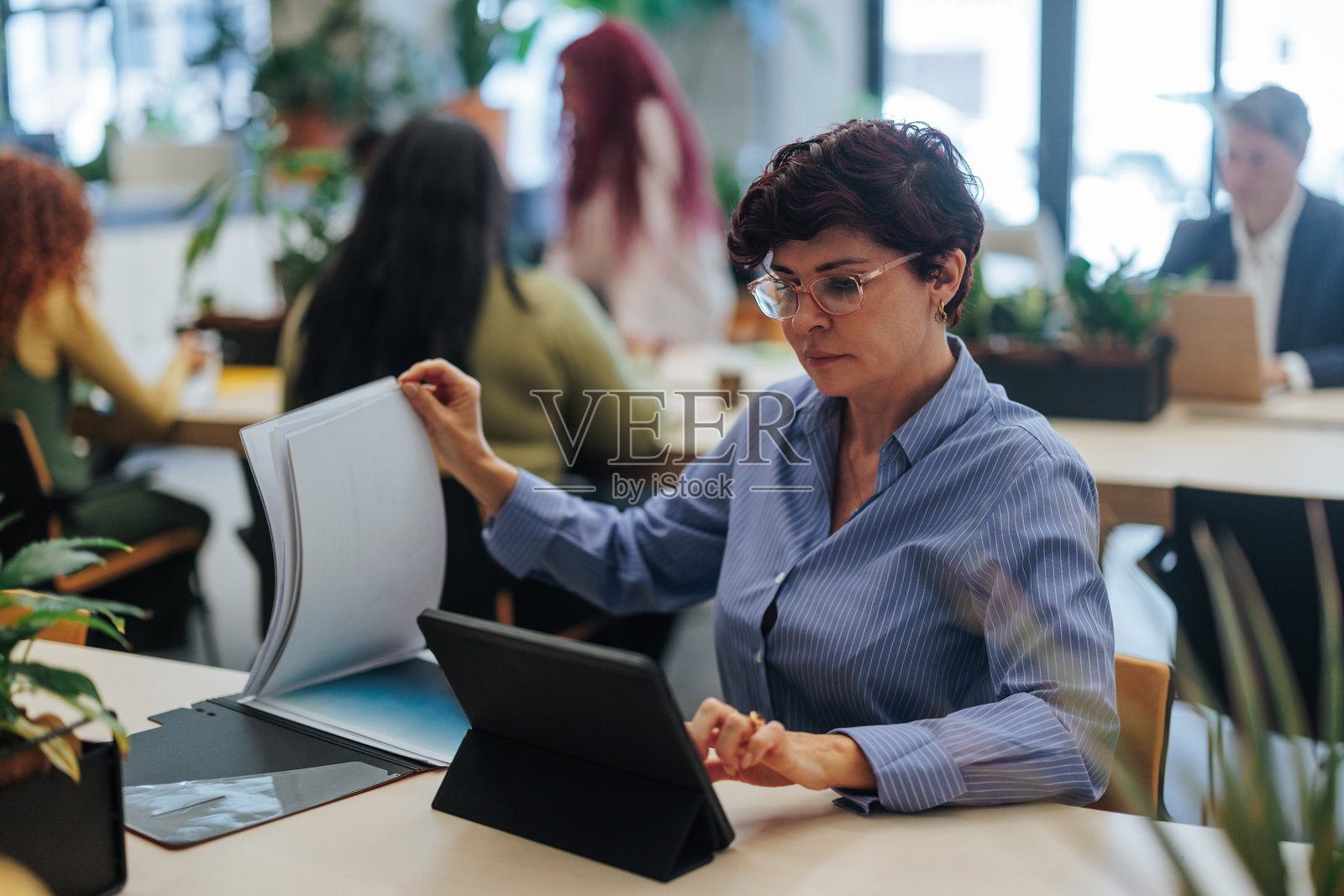 专注的员工在繁忙的办公室中浏览数字平板和阅读文件照片摄影图片