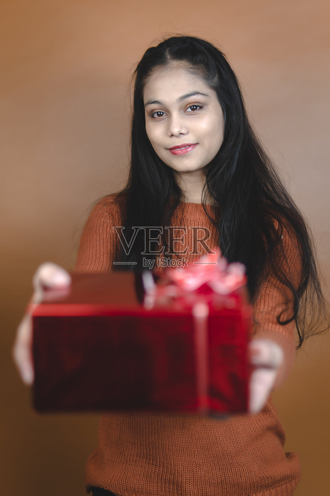 年轻女性手持红色礼品盒。照片摄影图片