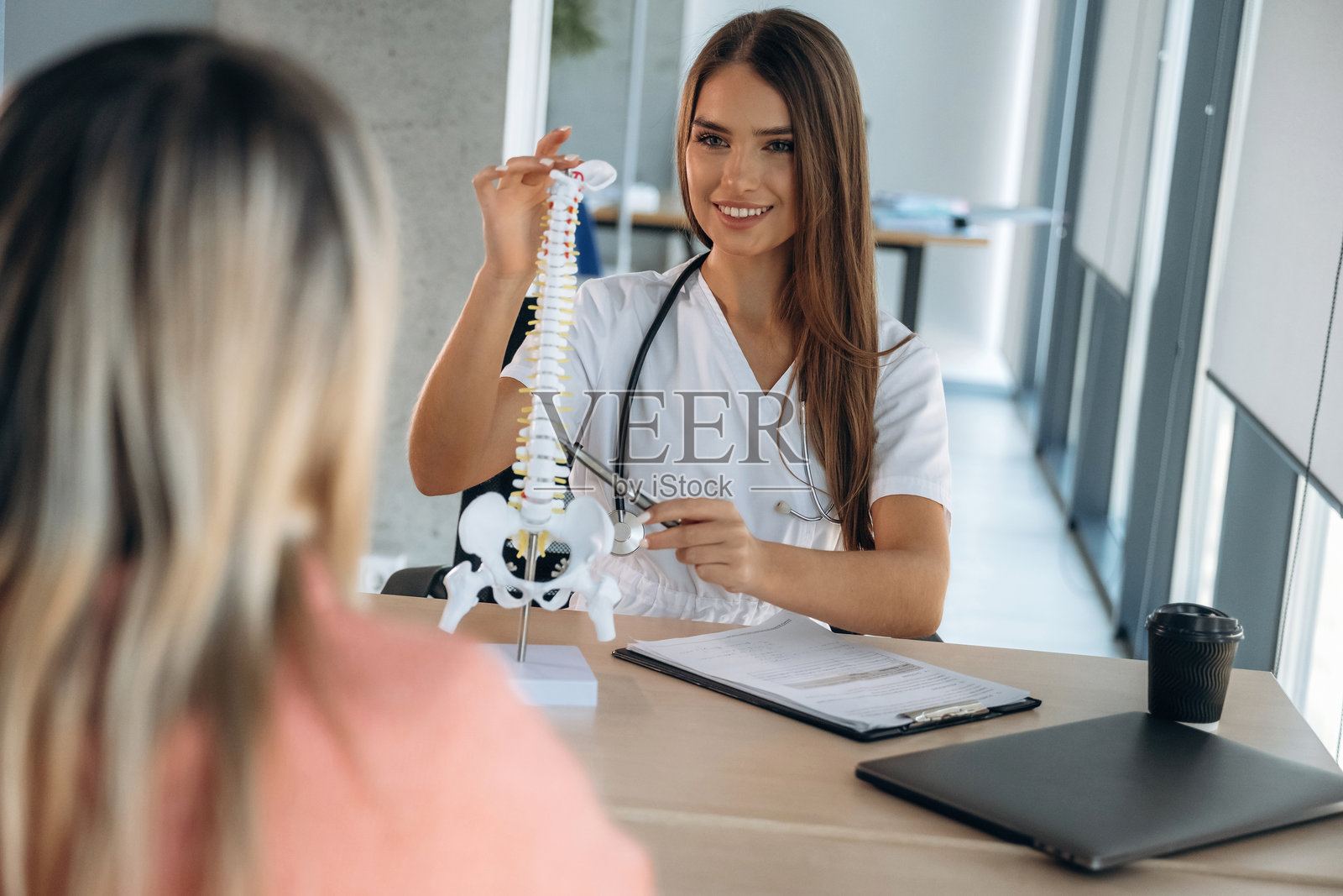 脊柱问题,展示模型上的问题。女性在诊所与医生进行咨询。照片摄影图片
