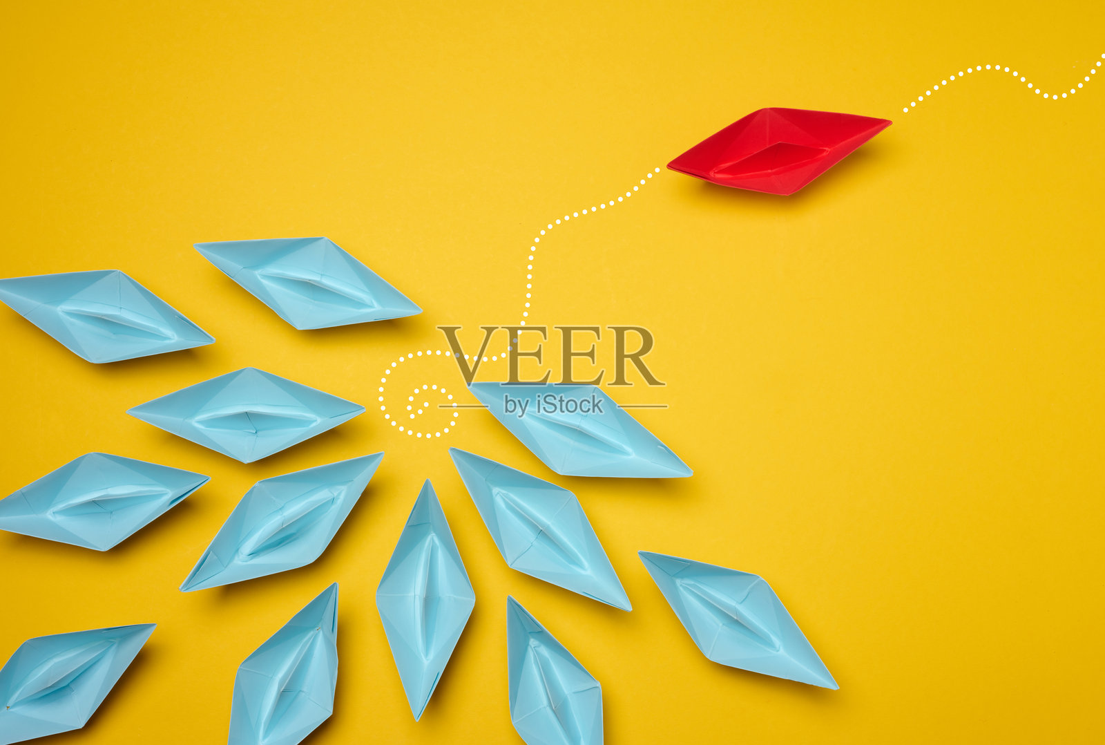 一群蓝色纸船朝一个方向行驶,而一只红色纸船朝相反方向行驶。体现了员工的个性、独特性和才能。照片摄影图片