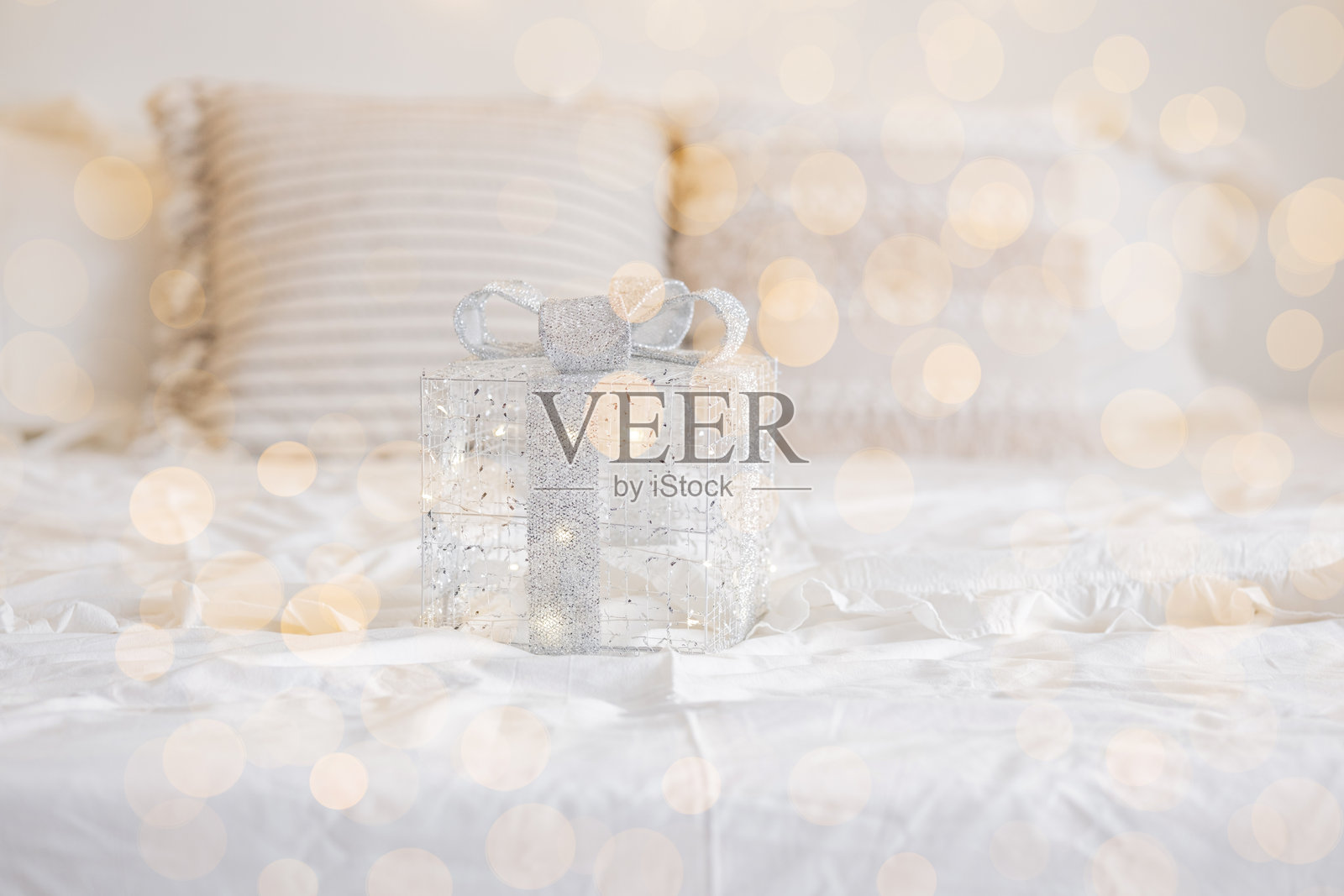 装饰性礼品盒,上面有银色蝴蝶结,放在白色床上。照片摄影图片