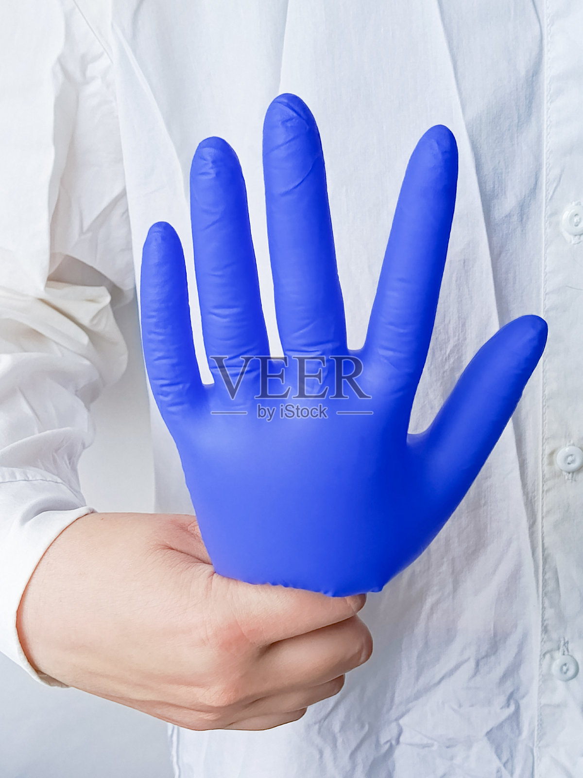 穿着白色医用外套的医生手中拿着医疗手套。充气的蓝色手套。国际牙医日。国际医生日。照片摄影图片