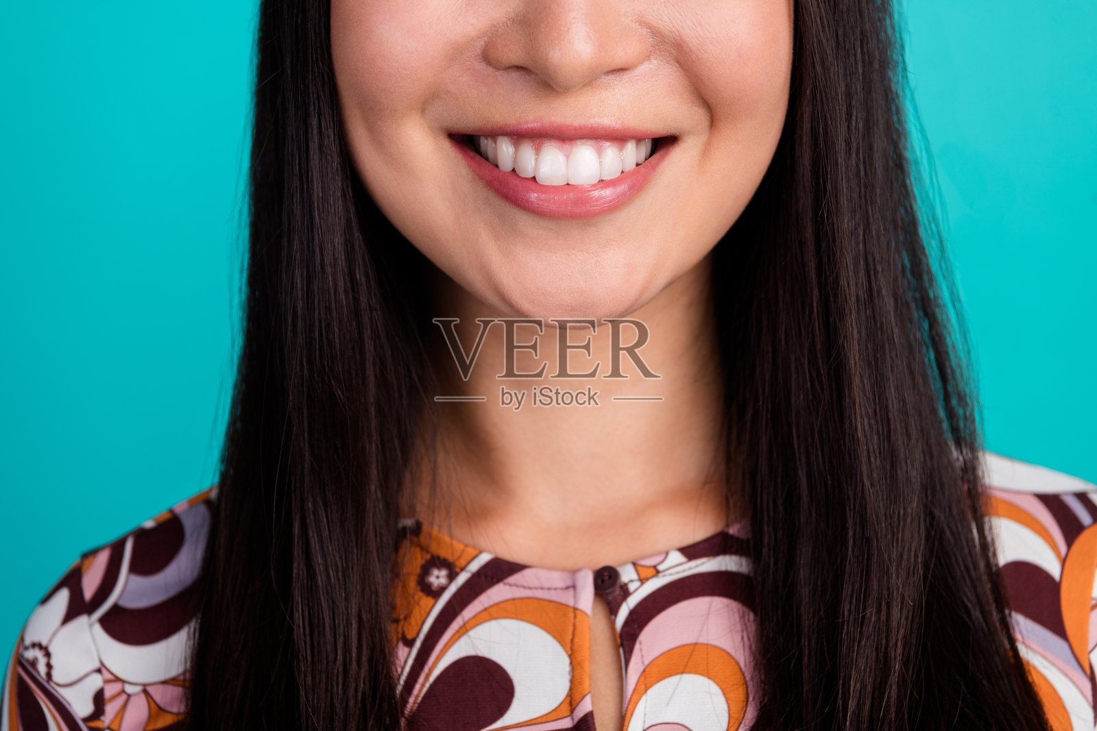 特写裁剪的年轻女孩面带灿烂笑容,背景为青绿色。照片摄影图片