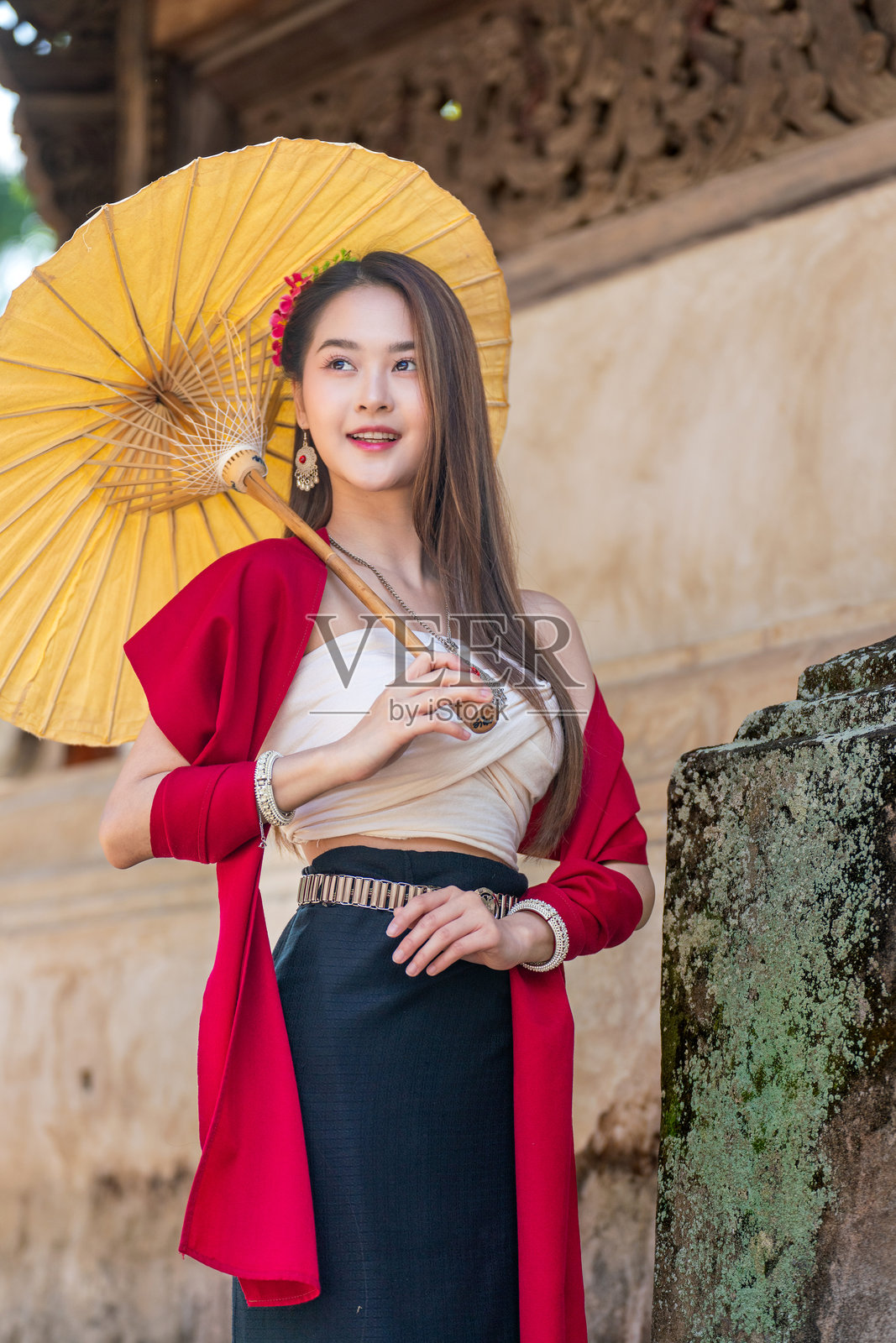 身穿传统兰纳泰国服饰的亚洲女性在清迈的因塔拉瓦寺手持手工伞照片摄影图片