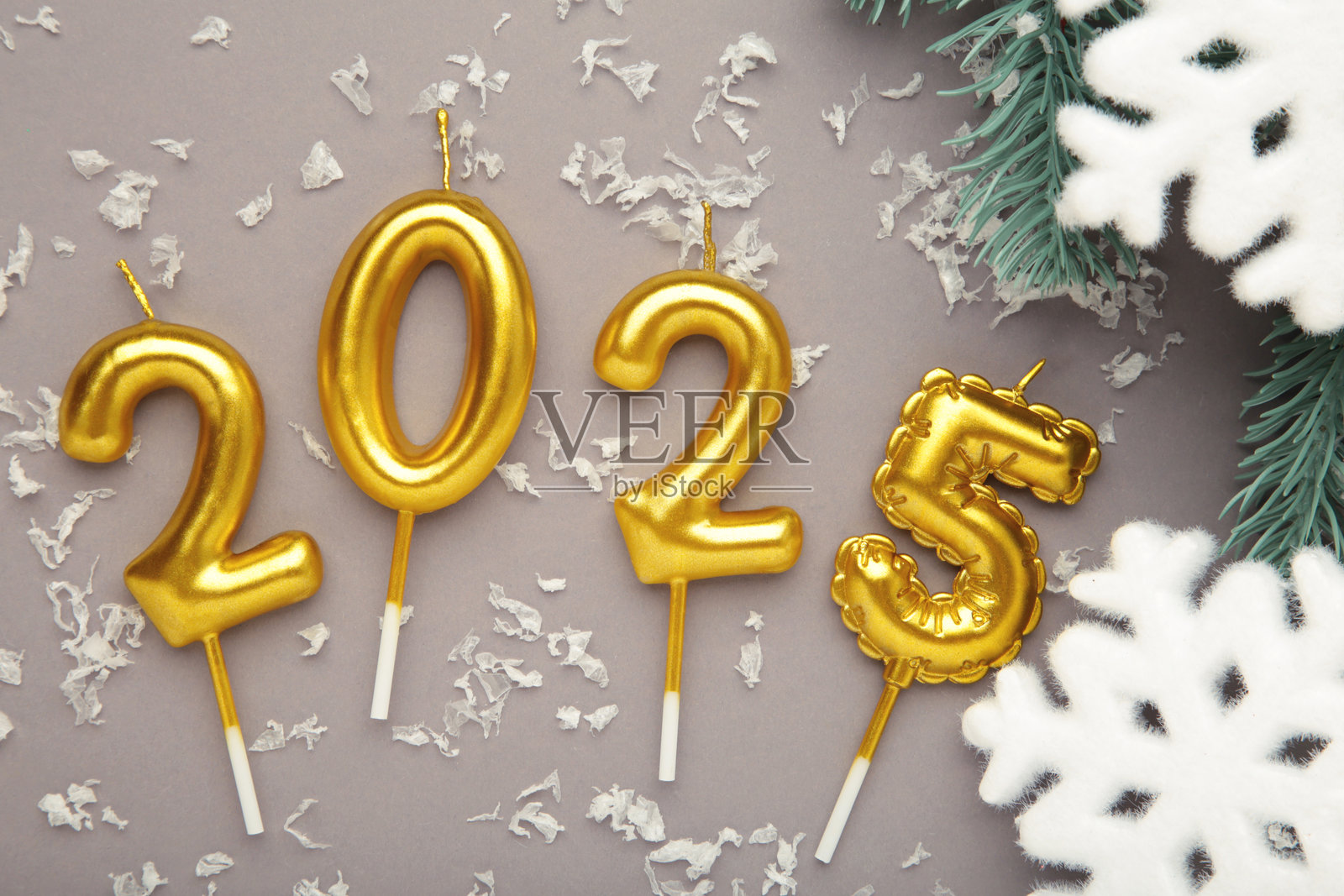节日背景快乐新年2025。2025的数字由金色蜡烛和灰色背景上的雪花组成。照片摄影图片
