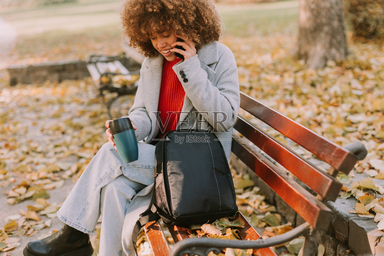 在风景如画的秋季公园中,享受着生动的对话,品味着咖啡,周围是五彩斑斓的落叶。照片摄影图片