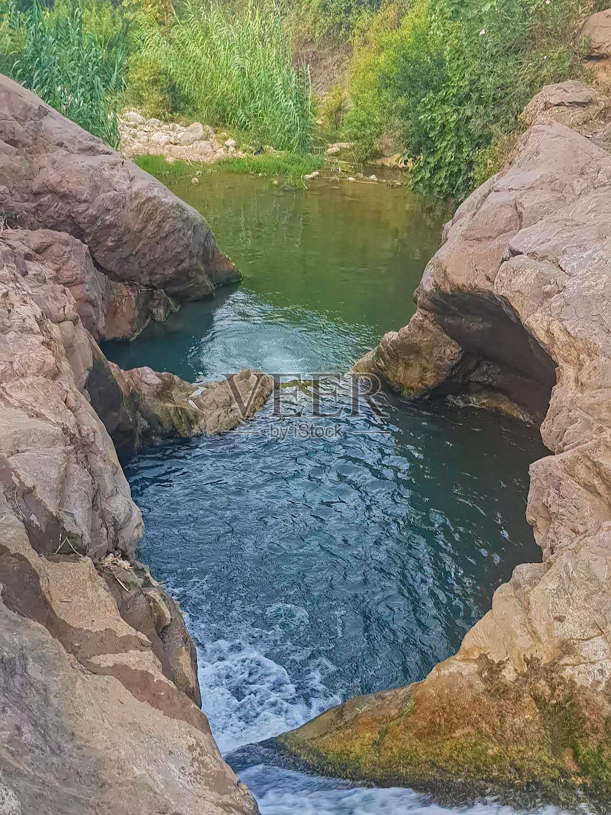 自然池塘坐落在风景如画的山谷中,四周环绕着崎岖的岩石 formations照片摄影图片