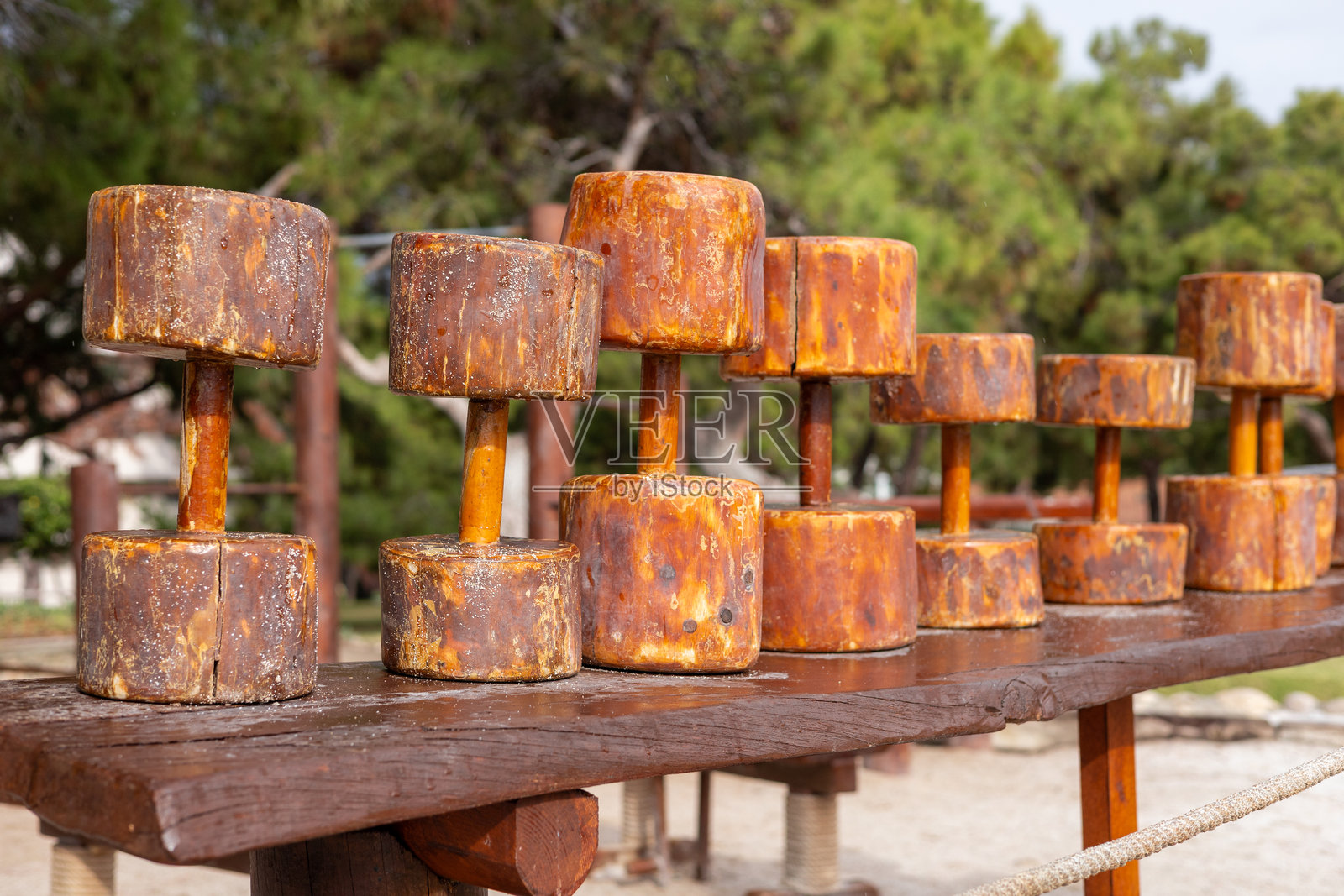 生锈的哑铃静静地放在阳光明媚的公园木长椅上照片摄影图片