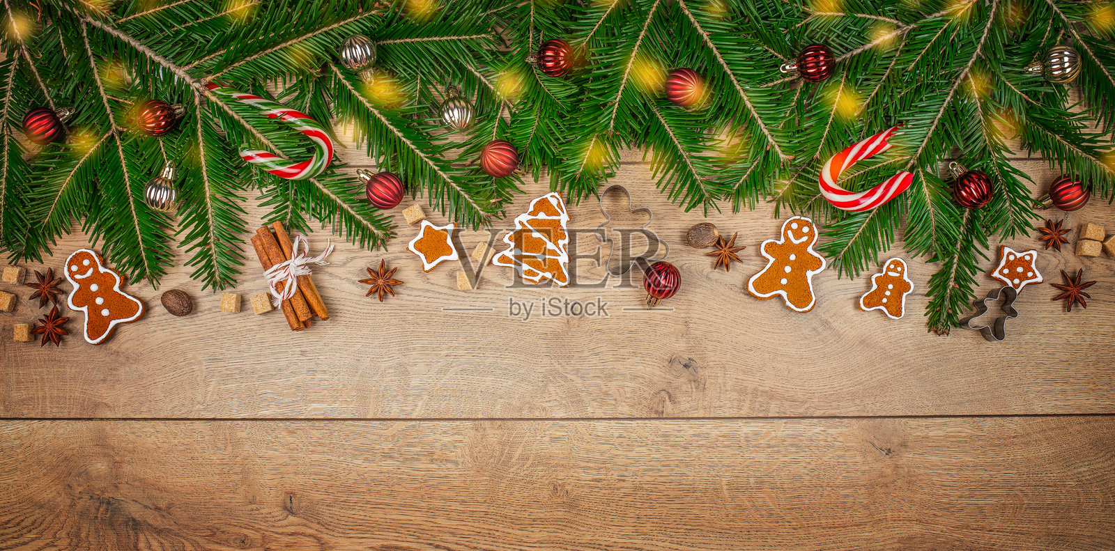 圣诞饼干、冷杉枝和圣诞灯饰在木桌上。长条横幅格式。俯视图。留白空间。照片摄影图片
